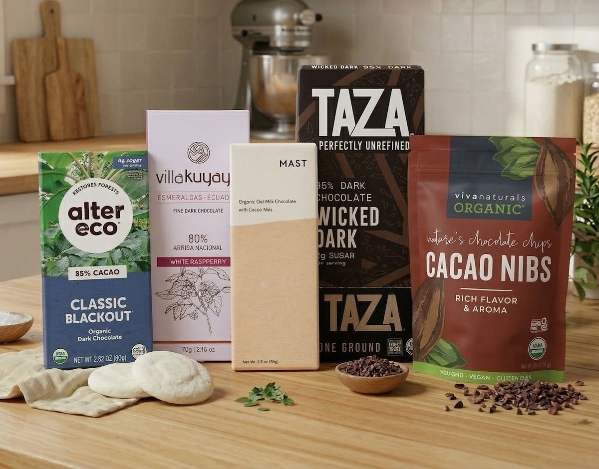 Premium organic chocolate bars and cacao nibs, featuring brands like Alter Eco and Mast, displayed on a wooden kitchen island.