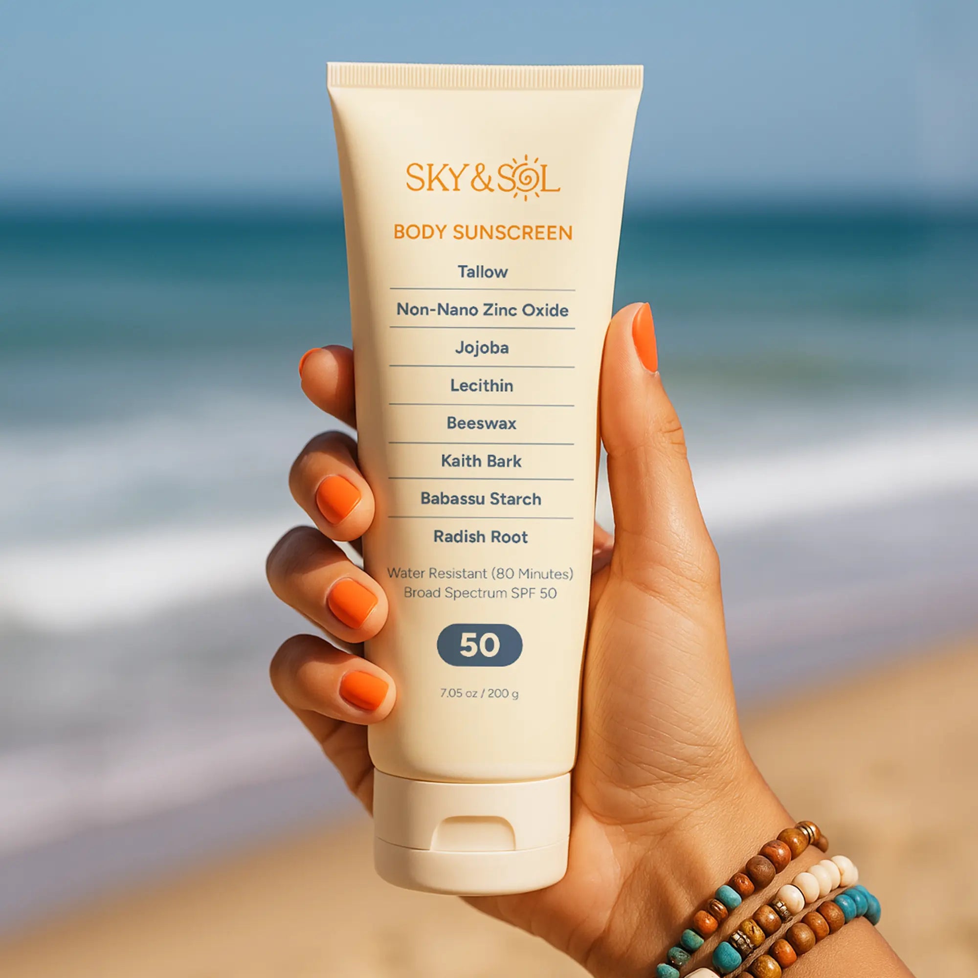 A woman's hand on the beach holding a tube of non toxic sunscreen