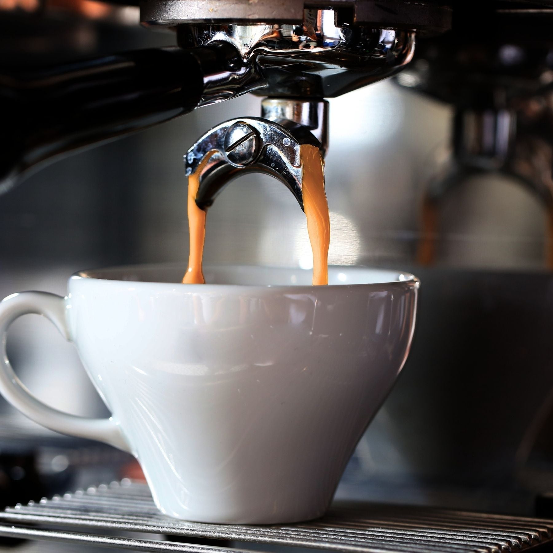 Espresso machine pouring fresh organic coffee into a glass.