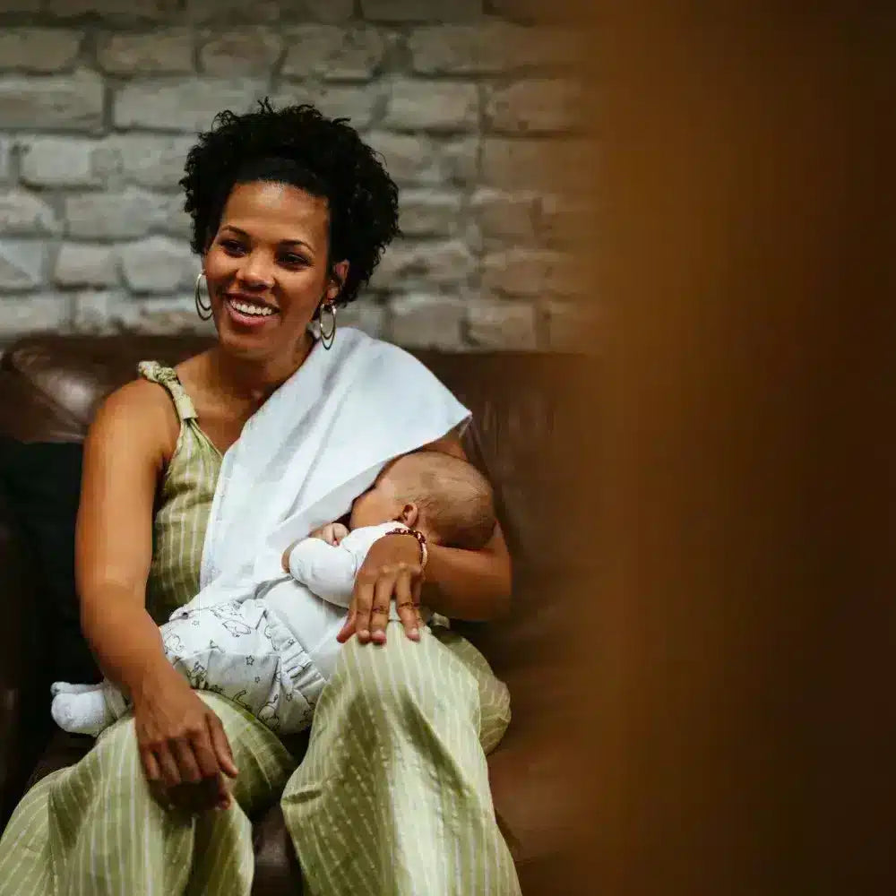Mother sitting on couch breastfeeding her baby