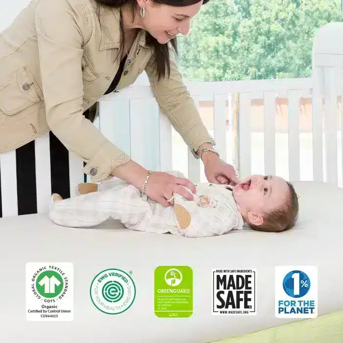 A mother resting her baby in a Naturepedic Classic Organic Seamless Crib Mattress