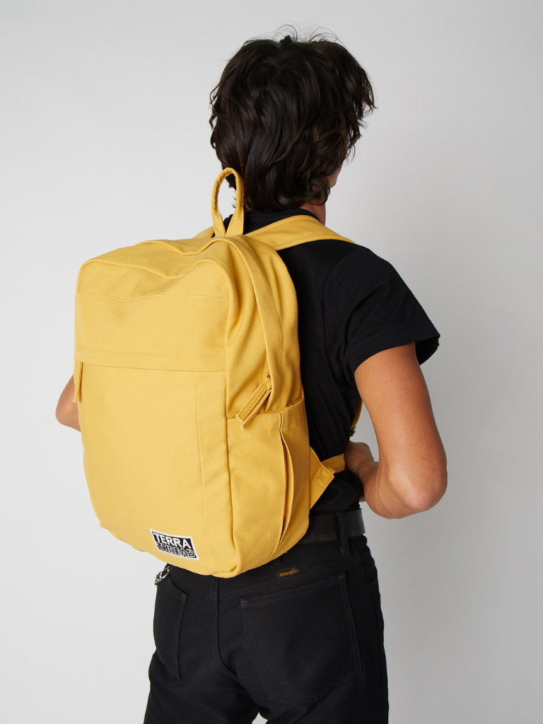Person wearing a yellow backpack on a plain background