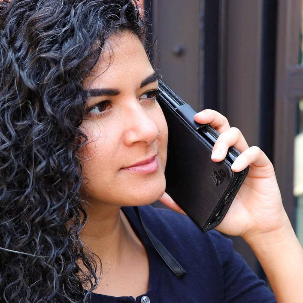 A young woman with dark wavy hair holding a cellphone with an EMF radiation protection case.