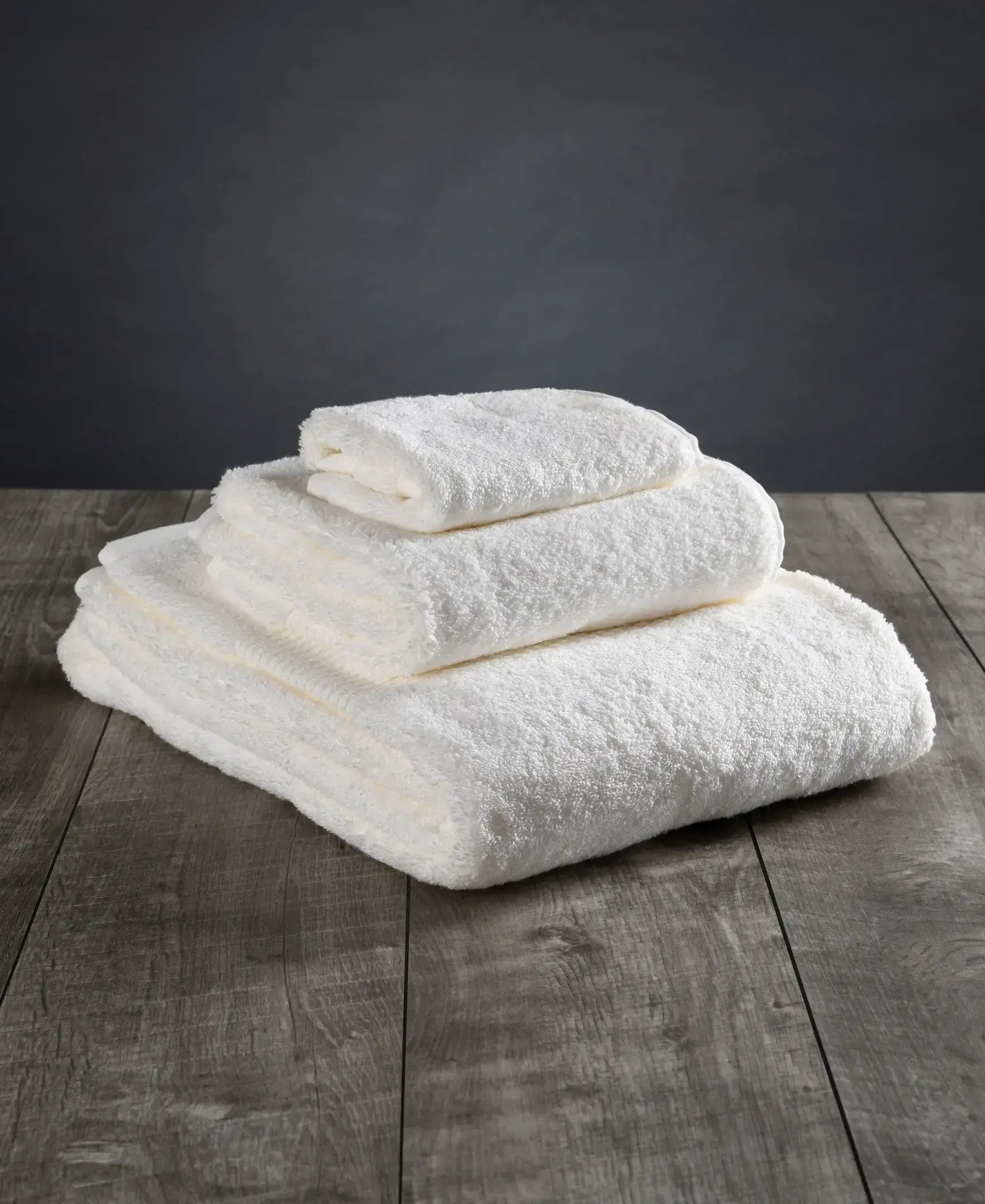 Stack of white towels on a wooden surface with a dark background