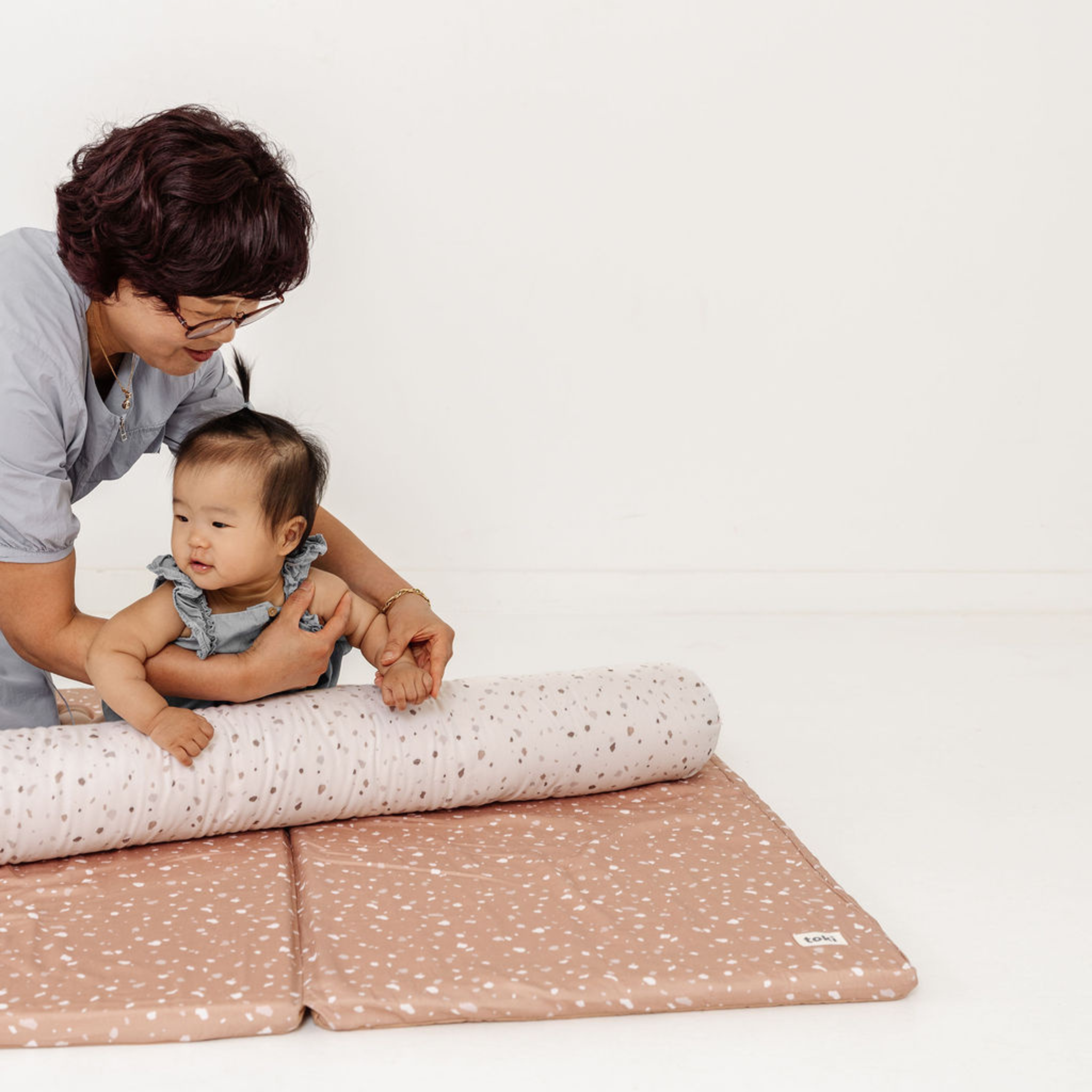 Woman and child playing on a pink and white patterned mat