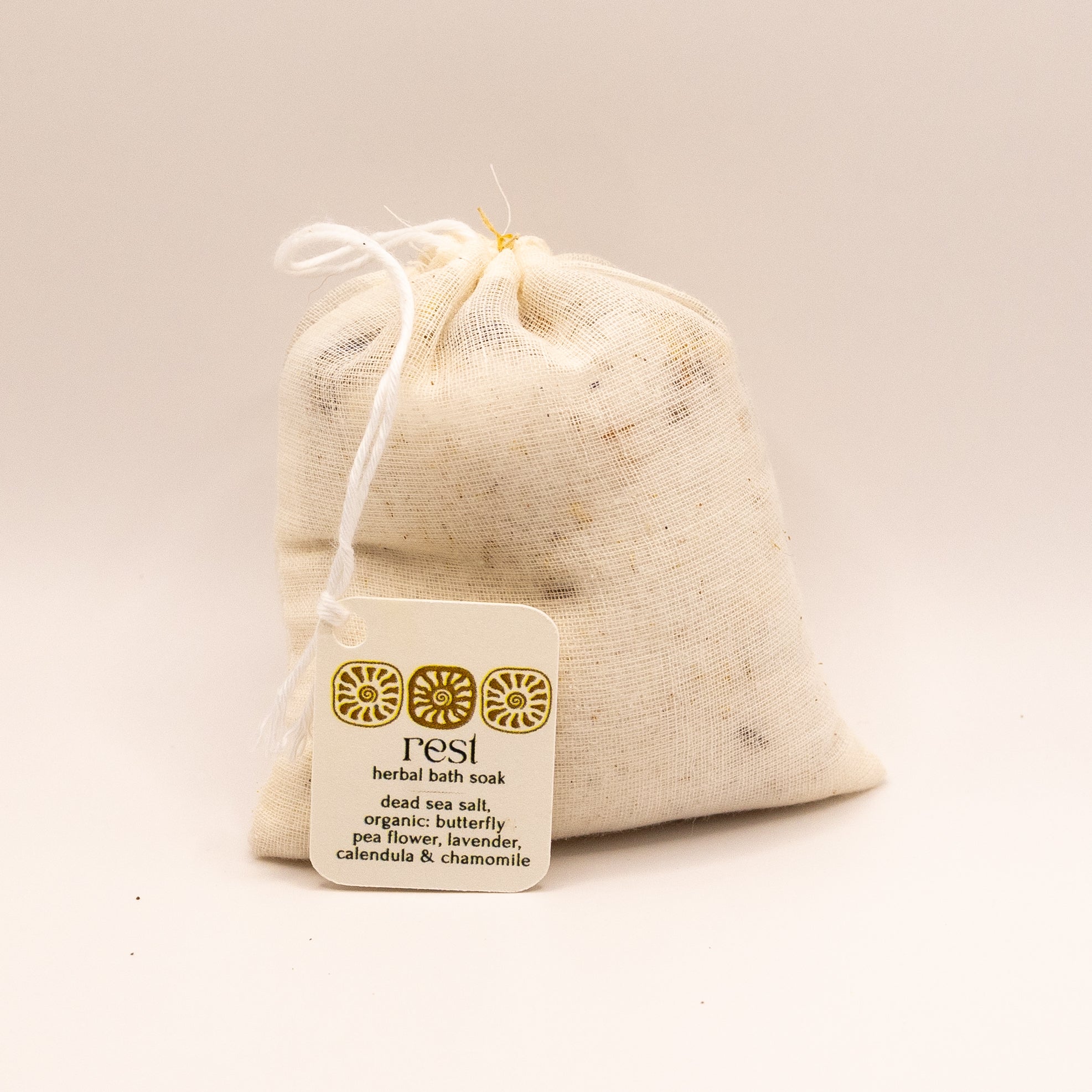 Herbal bath soak in a drawstring bag with a label on a beige background