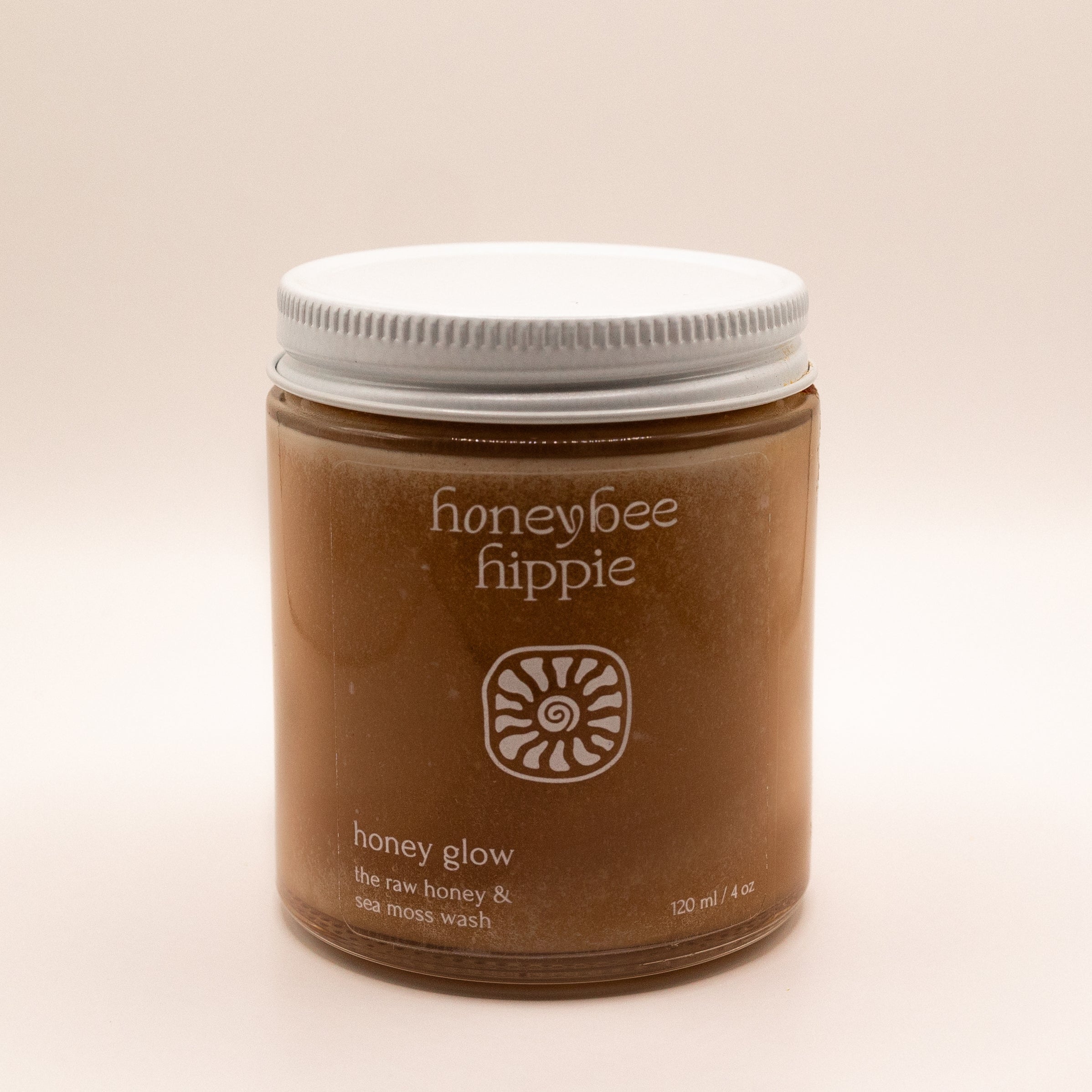Jar of honeybee hippie honey glow product on a beige background