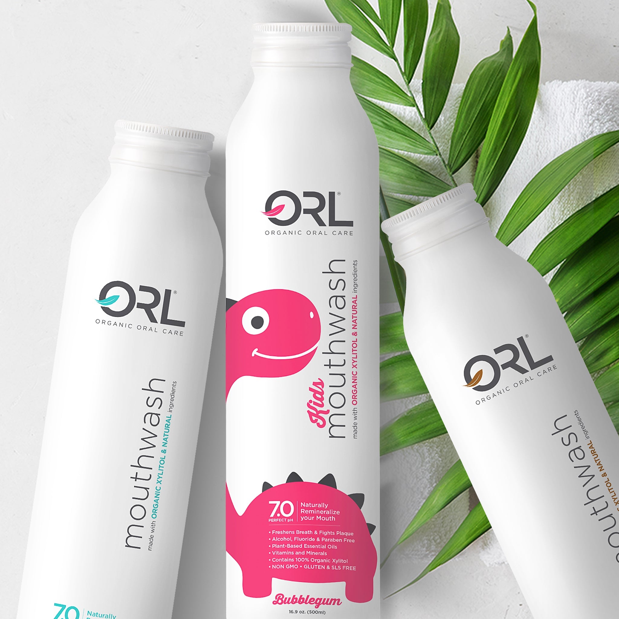 Three bottles of ORL Organic Oral Care mouthwash with a pink character on a white background.