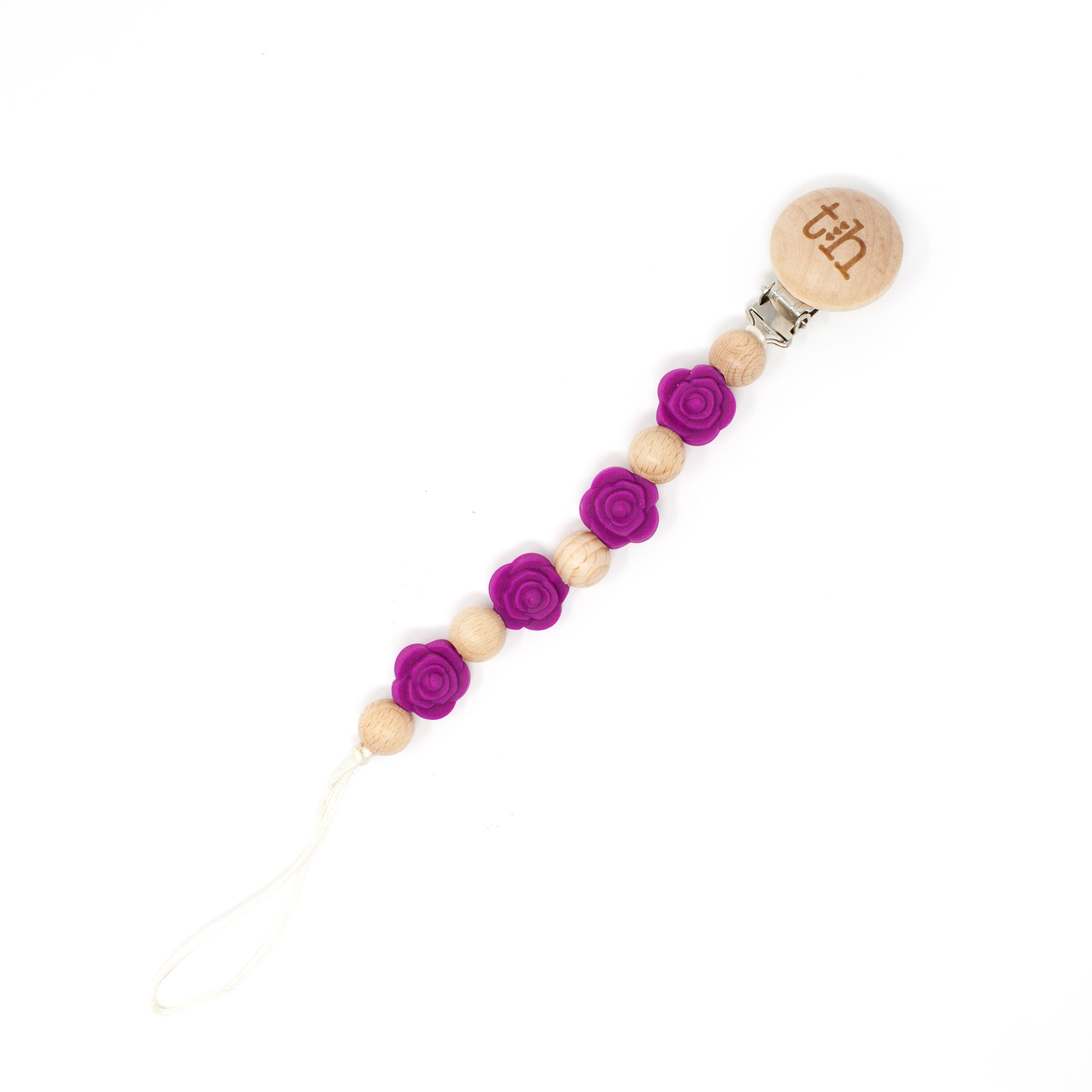 Wooden pacifier clip with purple flowers and a wooden bead on a white background