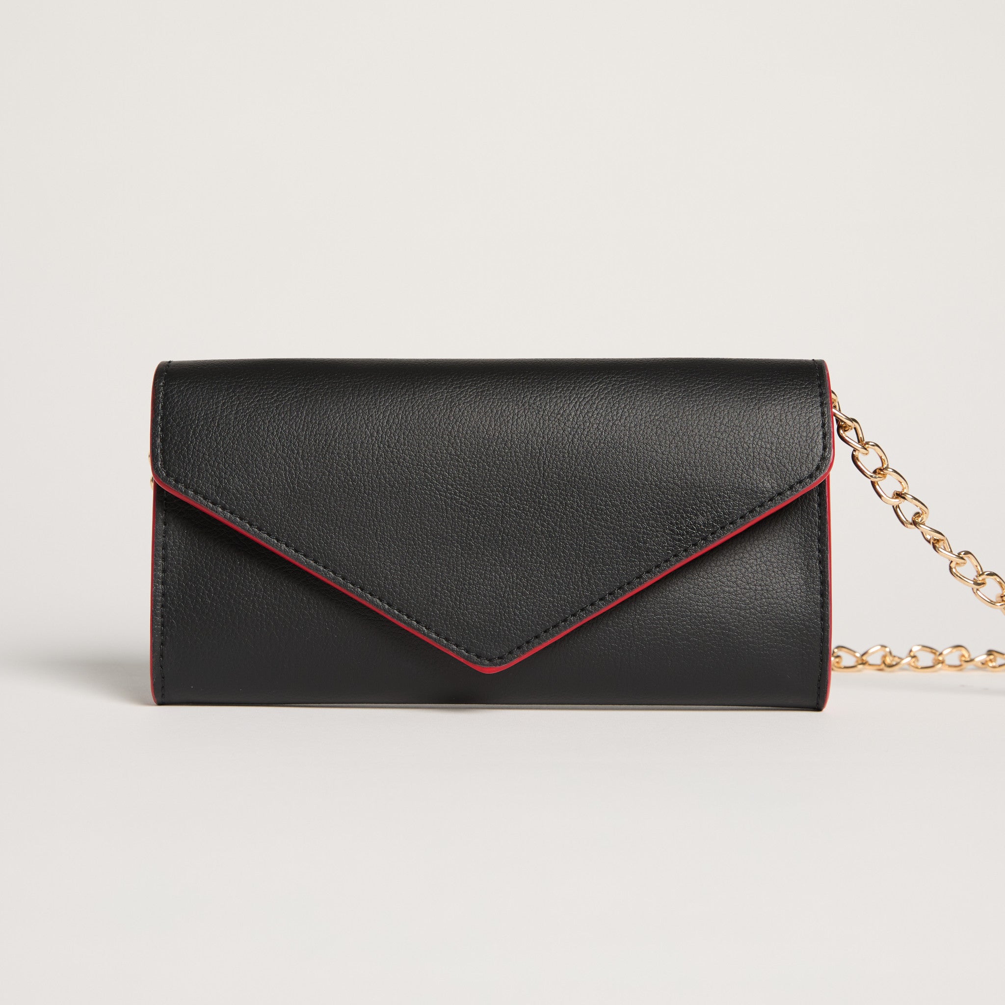 Black clutch bag with red interior lining and gold chain strap on a light gray background