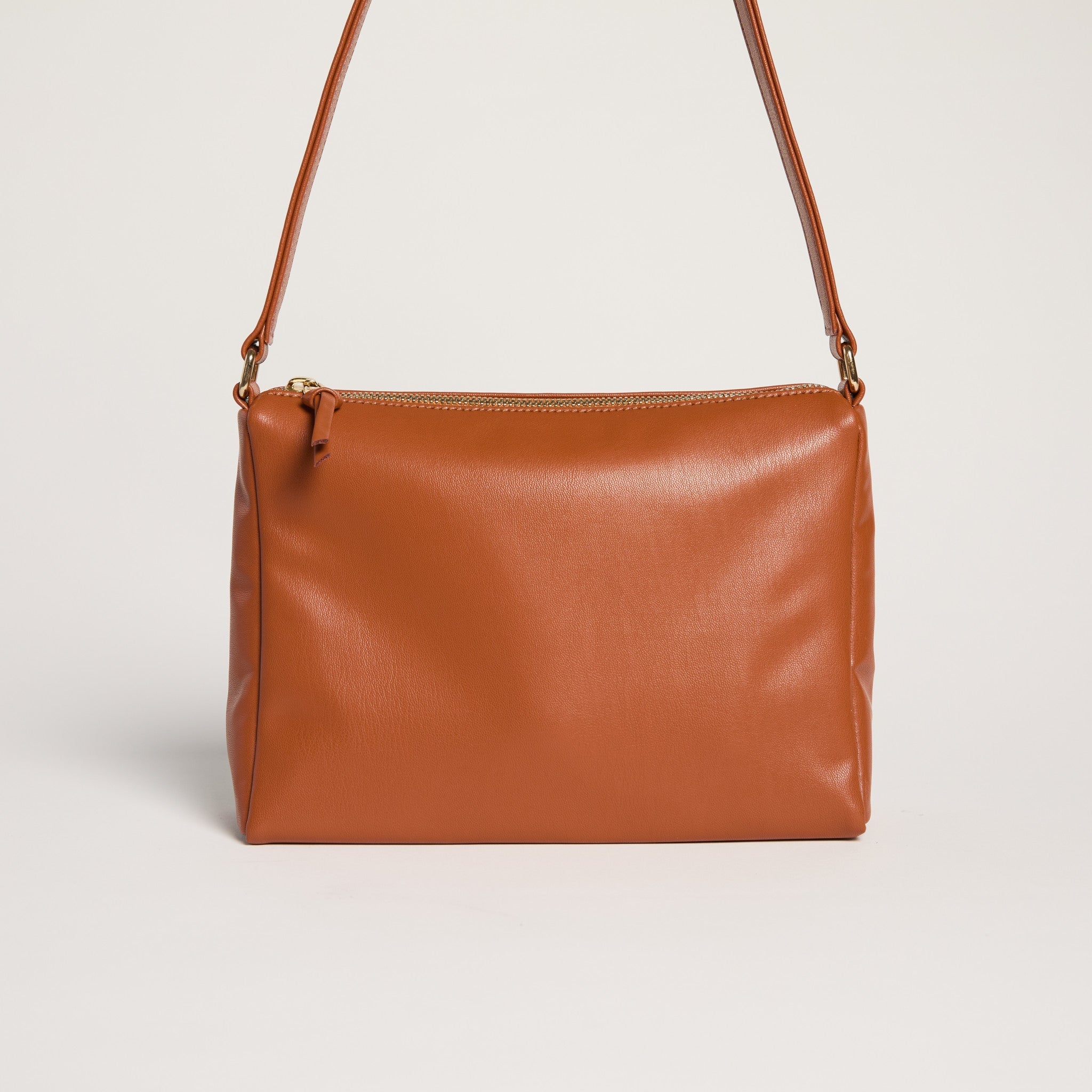 Brown leather handbag with a strap on a light gray background