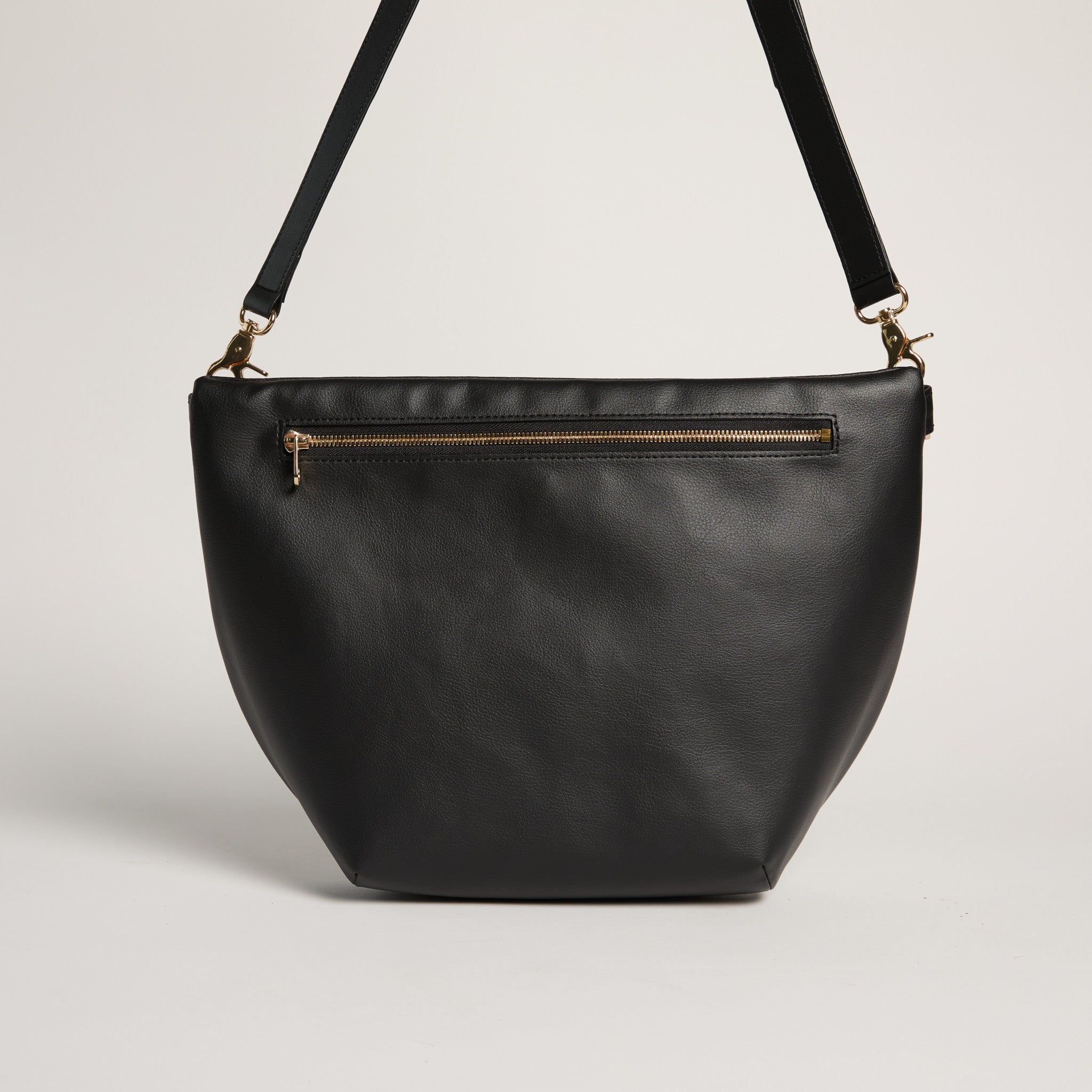 Black leather handbag with a gold zipper on a light gray background