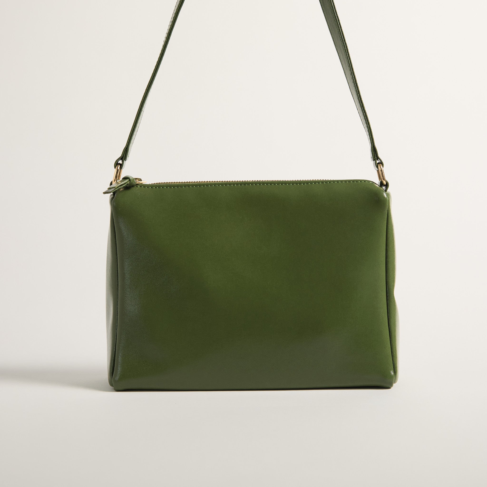 Green leather handbag with a strap on a light gray background