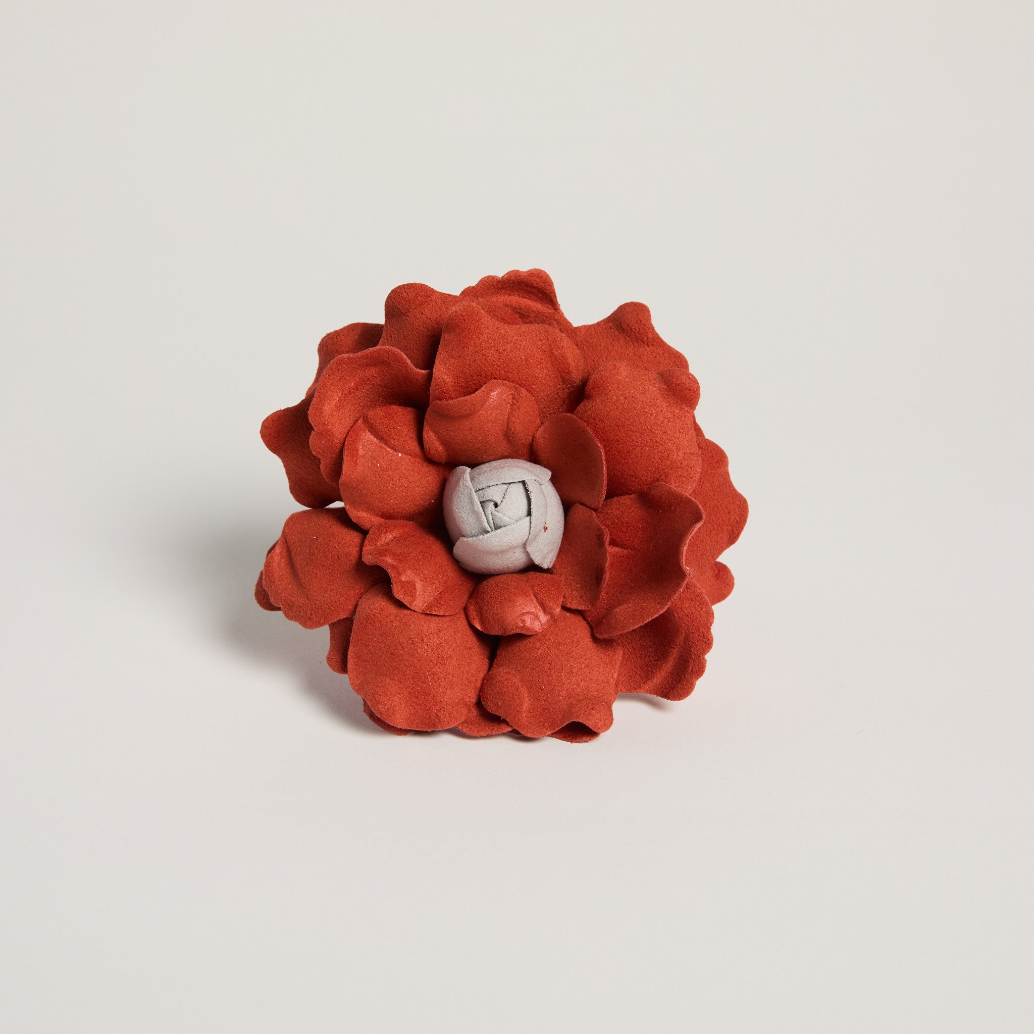 Red flower-shaped object with a white center on a light gray background