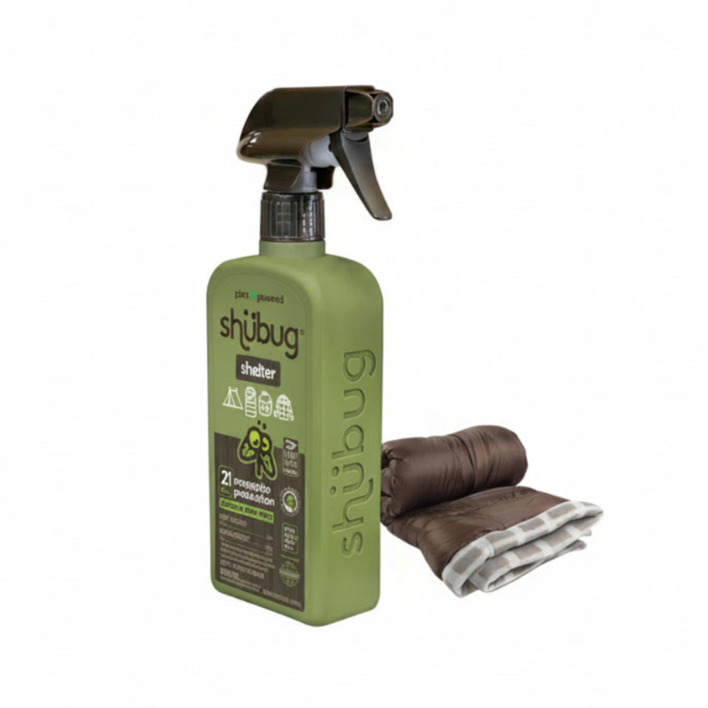 A bottle of Shubug Shelter 21 Flea Preventative spray in olive green with a dark brown trigger sprayer, shown next to a brown and white striped microfiber cloth on a plain white background.