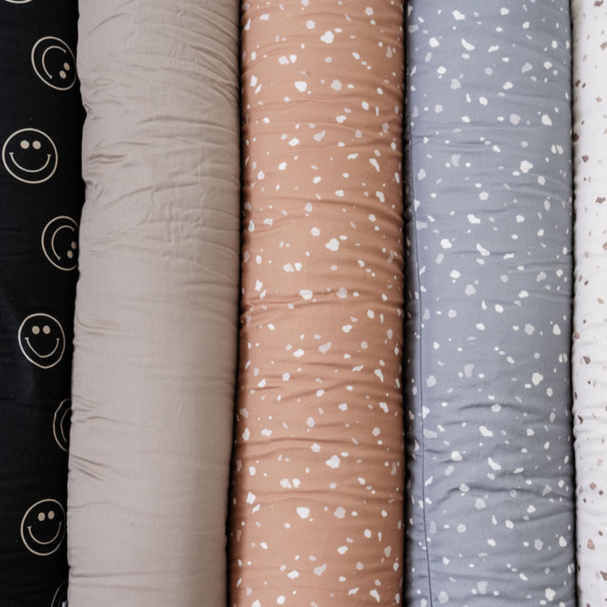 Row of textured fabric swatches in beige, pink, gray, and white.