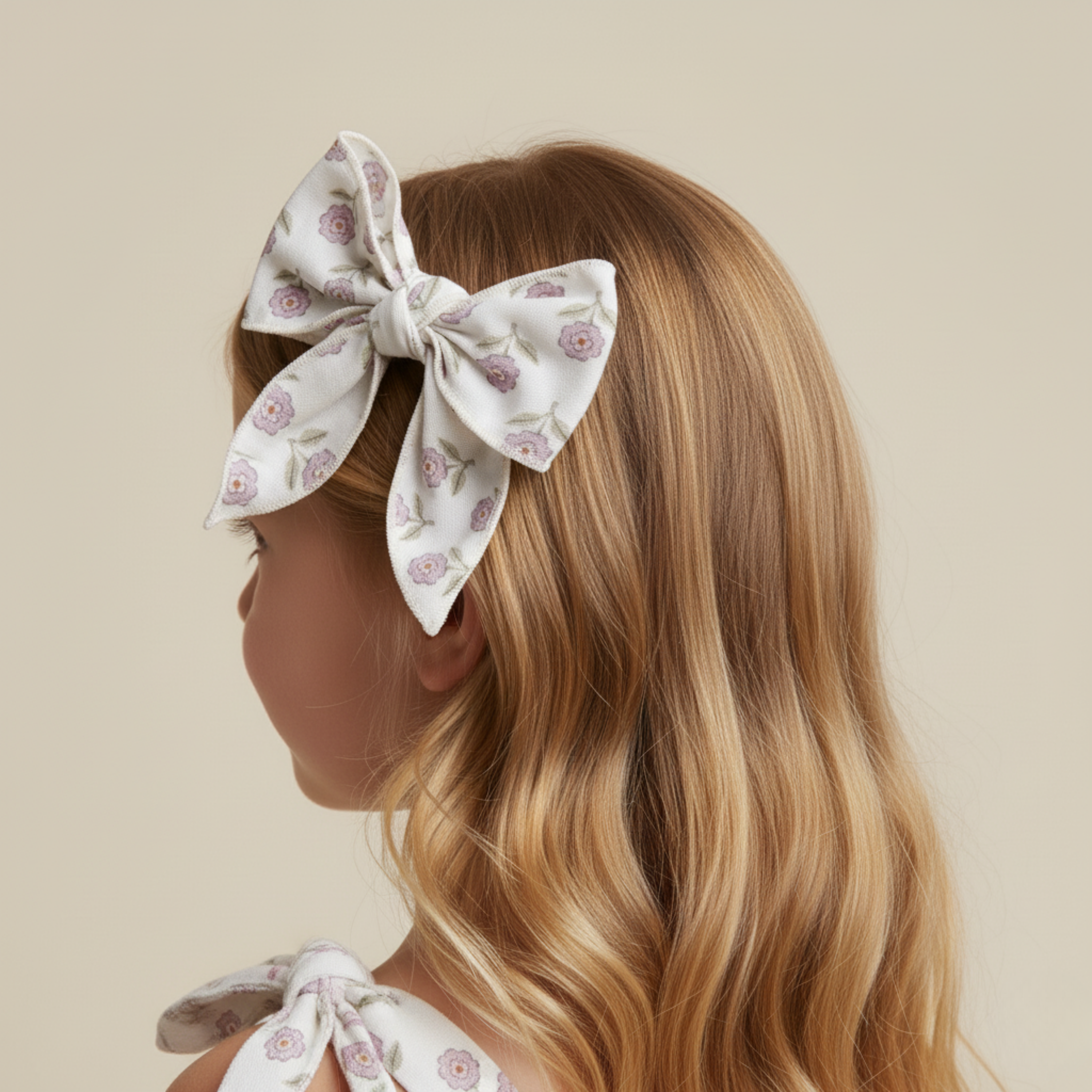 Woman with floral hair bow and matching outfit on a beige background