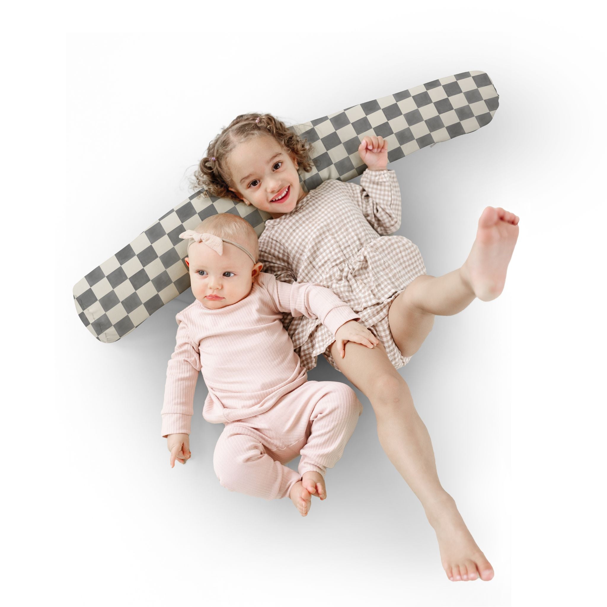 Two children lying on a checkered airplane toy on a white background