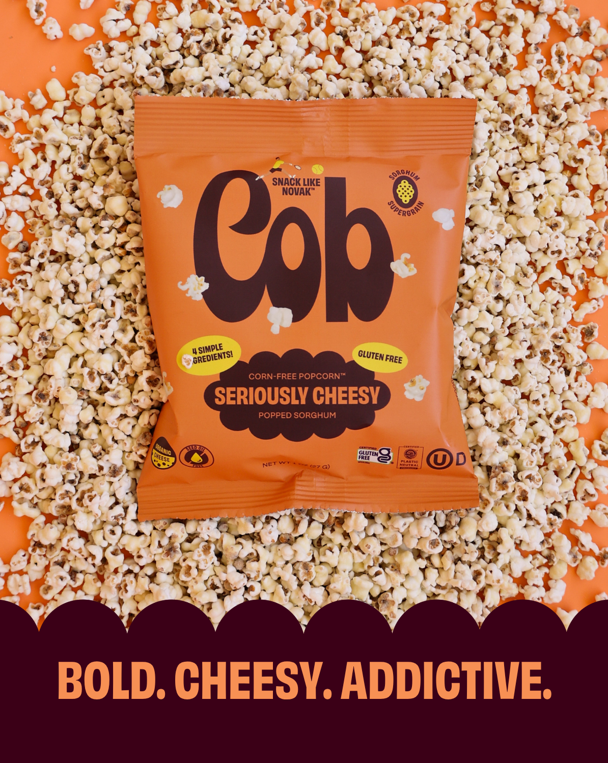 Orange 'Cob' popcorn bag surrounded by popcorn on an orange background with text 'Bold. Cheesy. Addictive.'