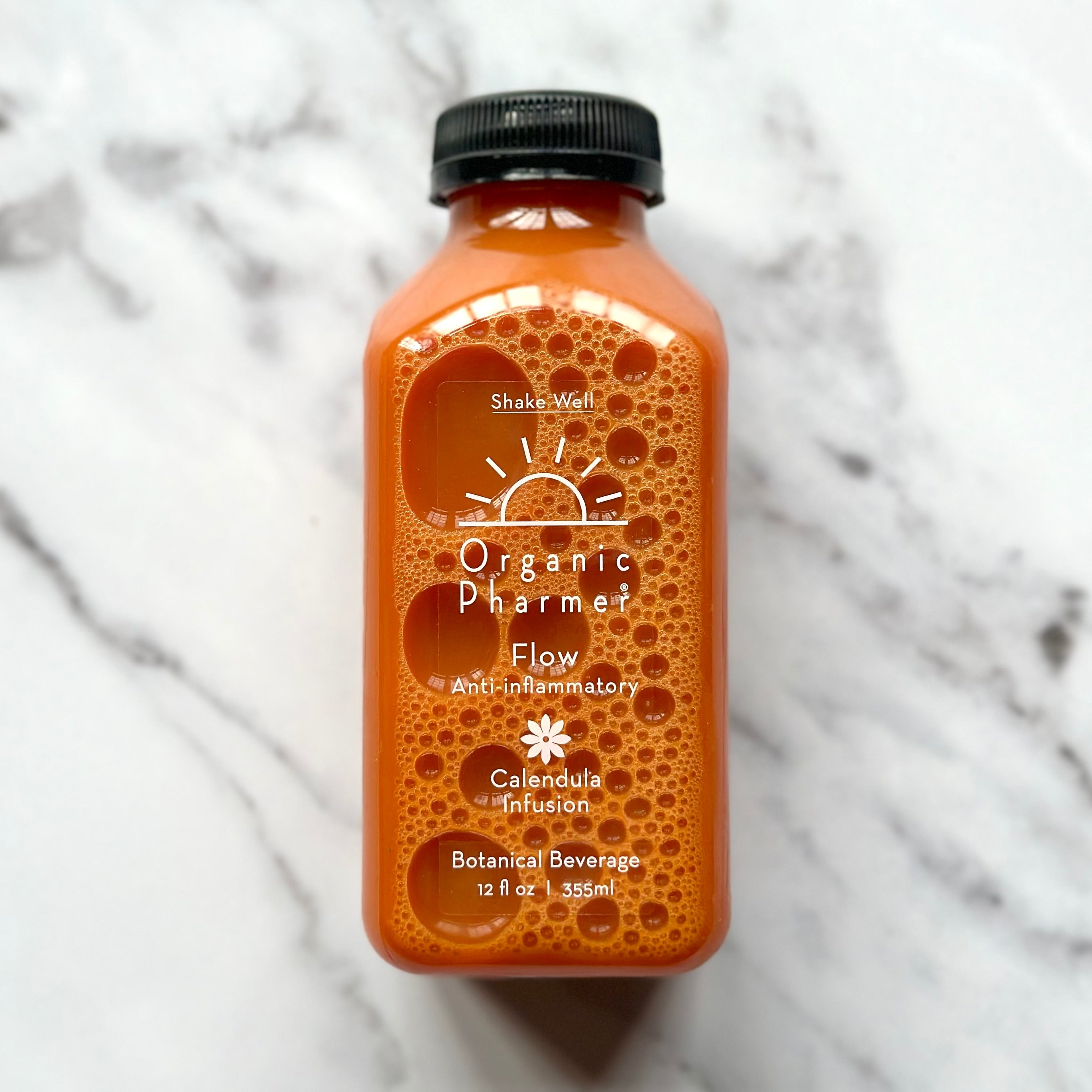 Orange bottle of Organic Pharmer botanical beverage on a marble surface