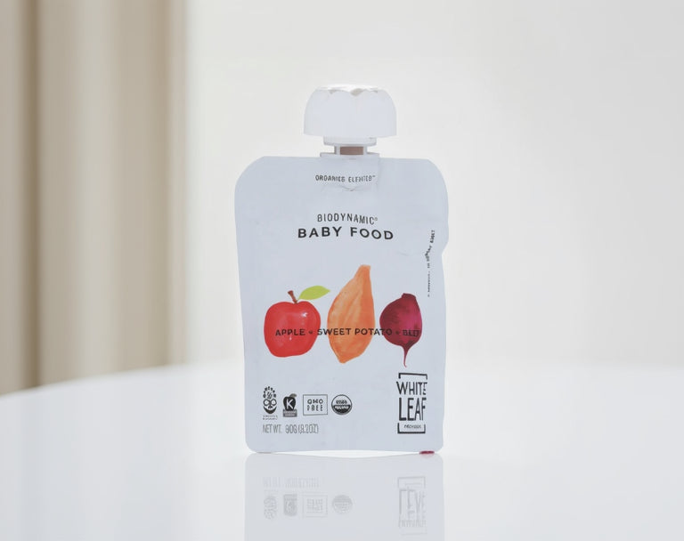 White Leaf Biodynamic baby food pouch with apple, sweet potato, and beet illustration on a white background