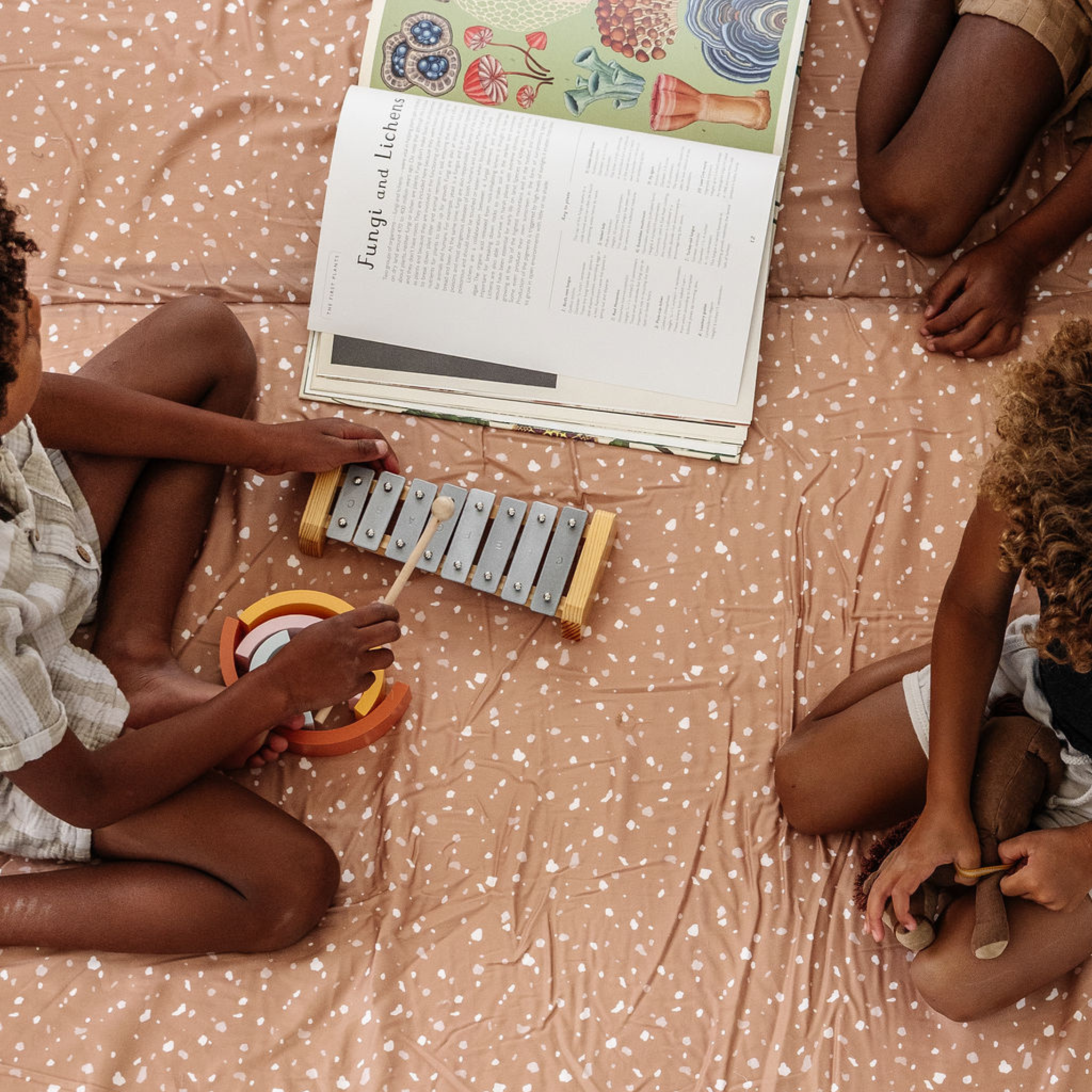 Two children playing with musical instruments on a patterned blanket