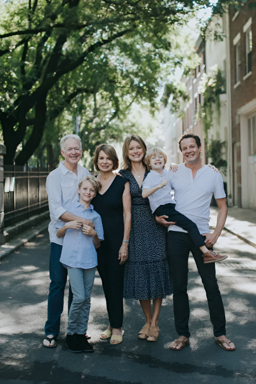 Family of six posing outdoors on a sunny day