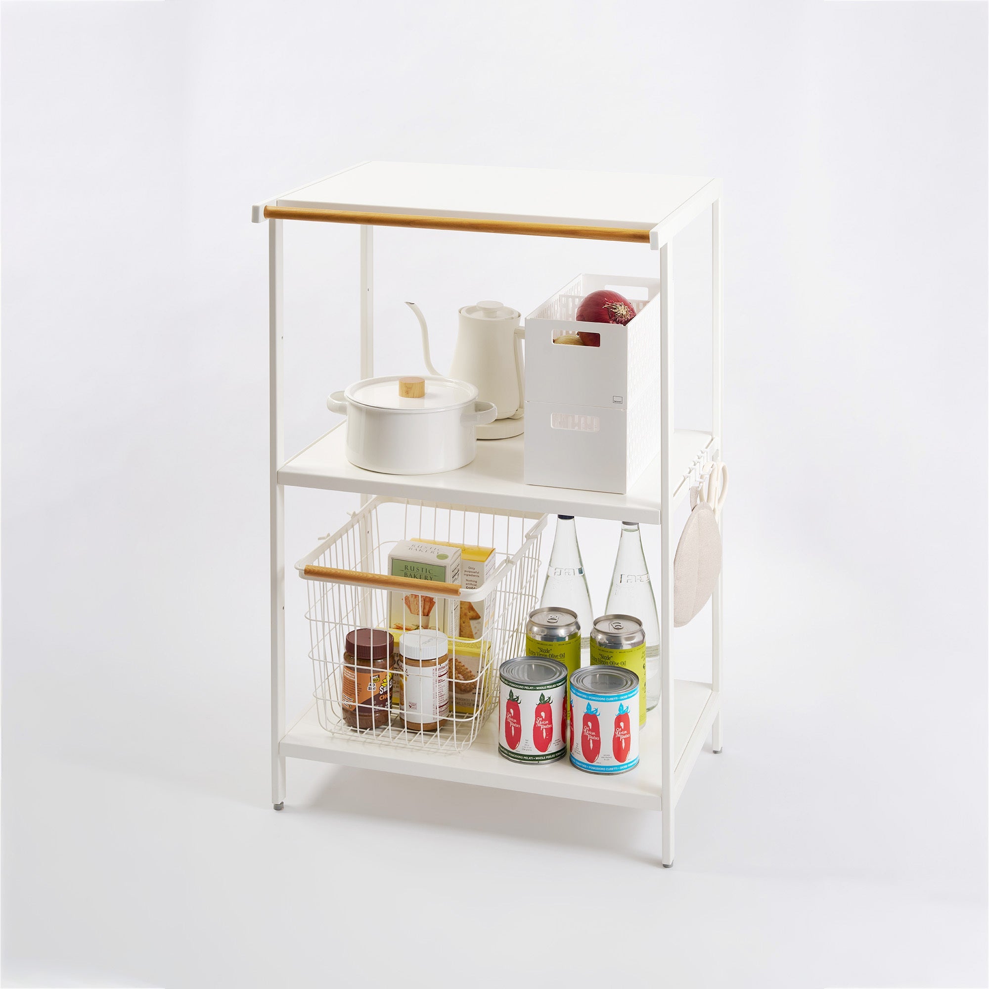 White metal kitchen cart with wooden handle holding various items on a white background