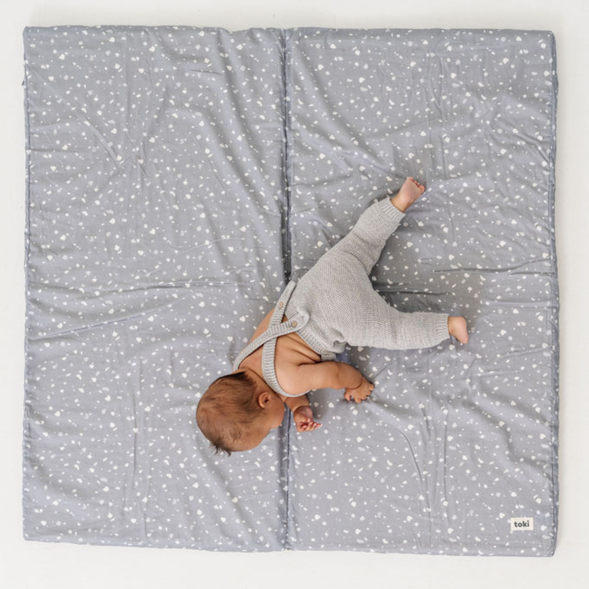 Baby lying on a gray blanket with white star pattern