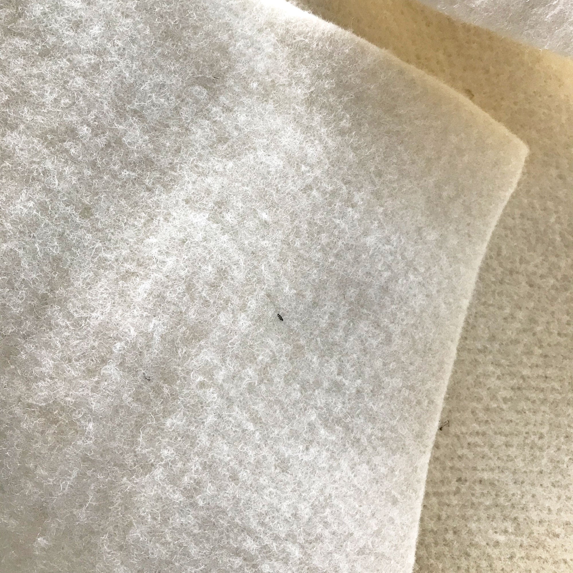 Close-up of a textured white fabric with a beige background