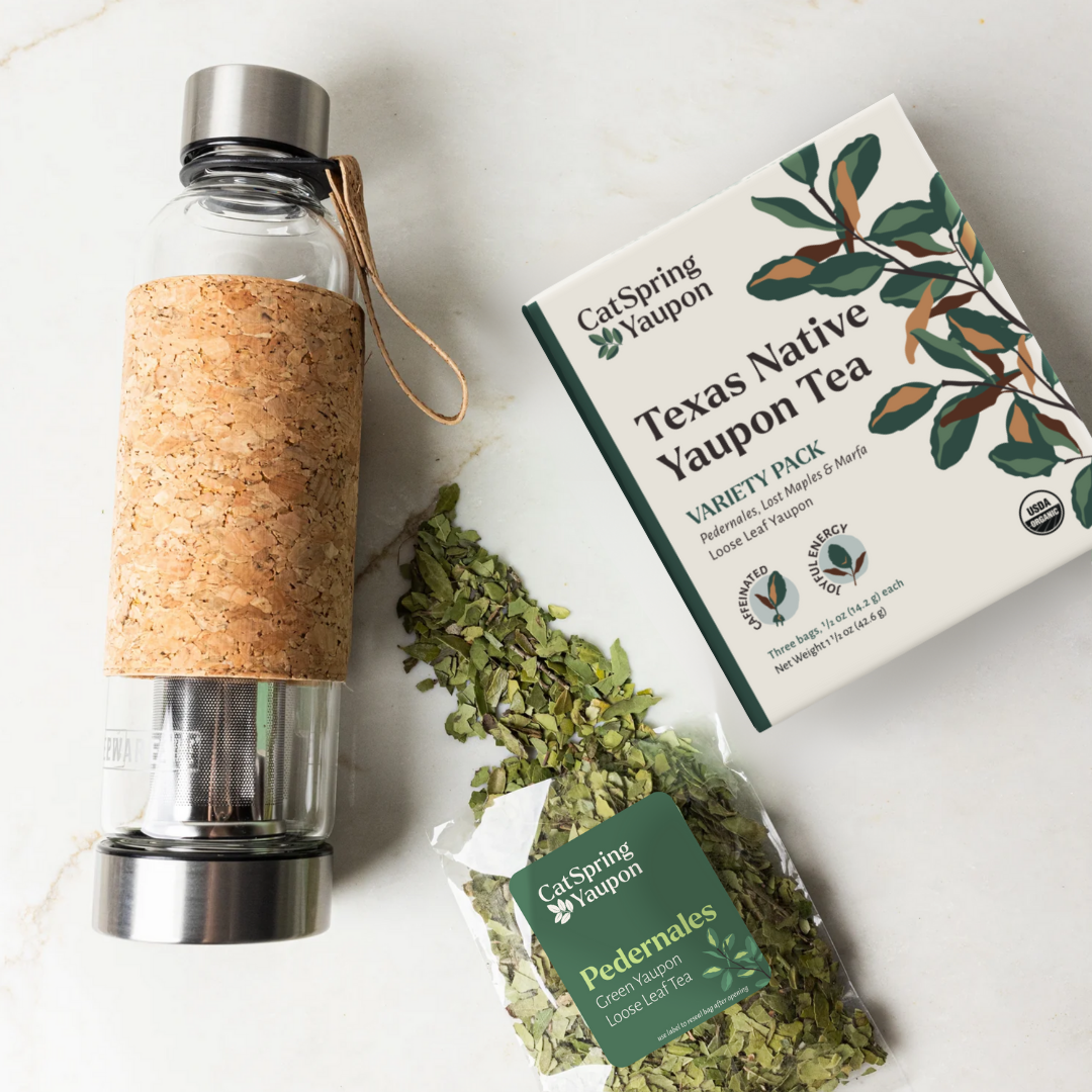 Clear glass water bottle with cork sleeve, box of Texas Native Yaupon Tea, and dried tea leaves on a white background