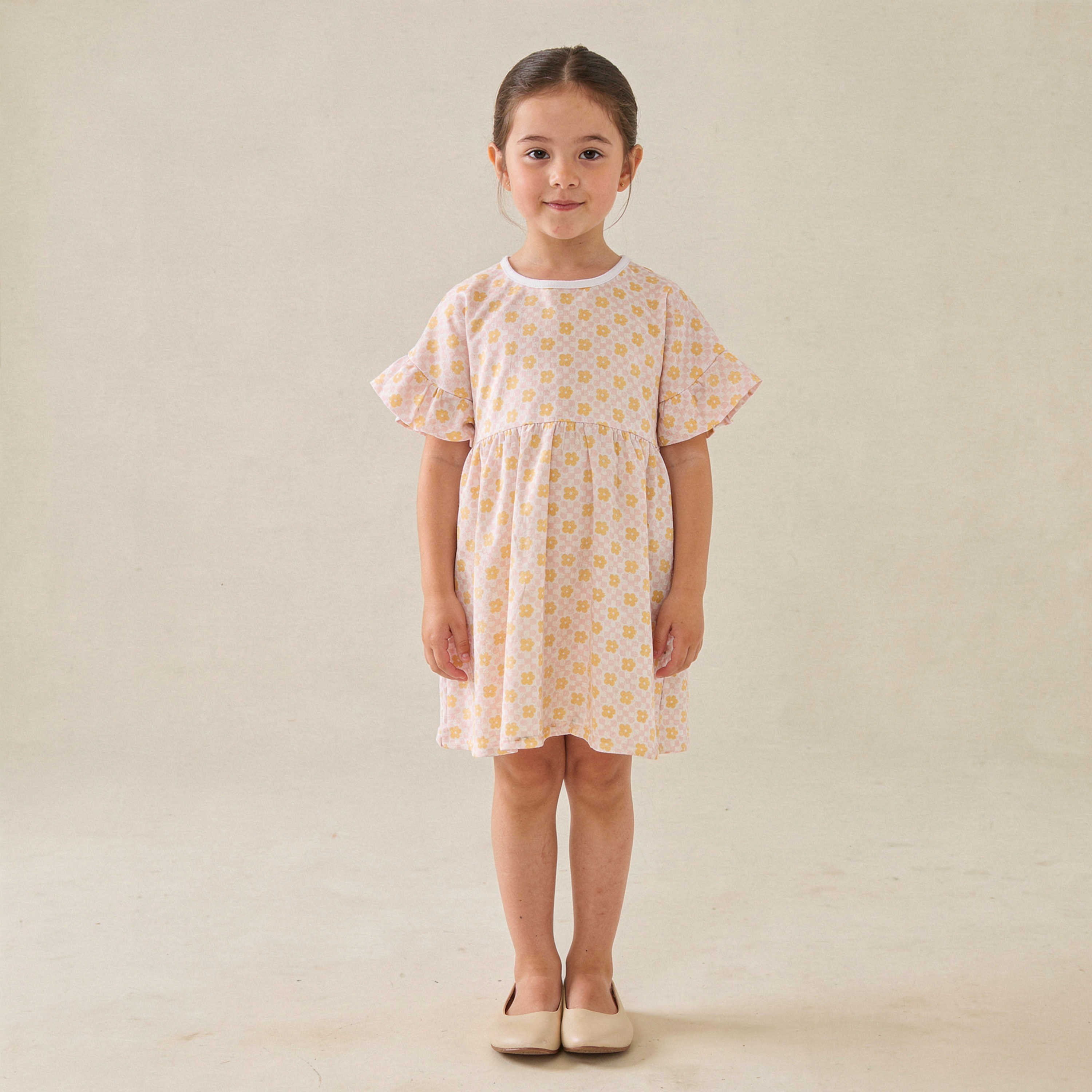 Young girl wearing a floral dress against a plain background