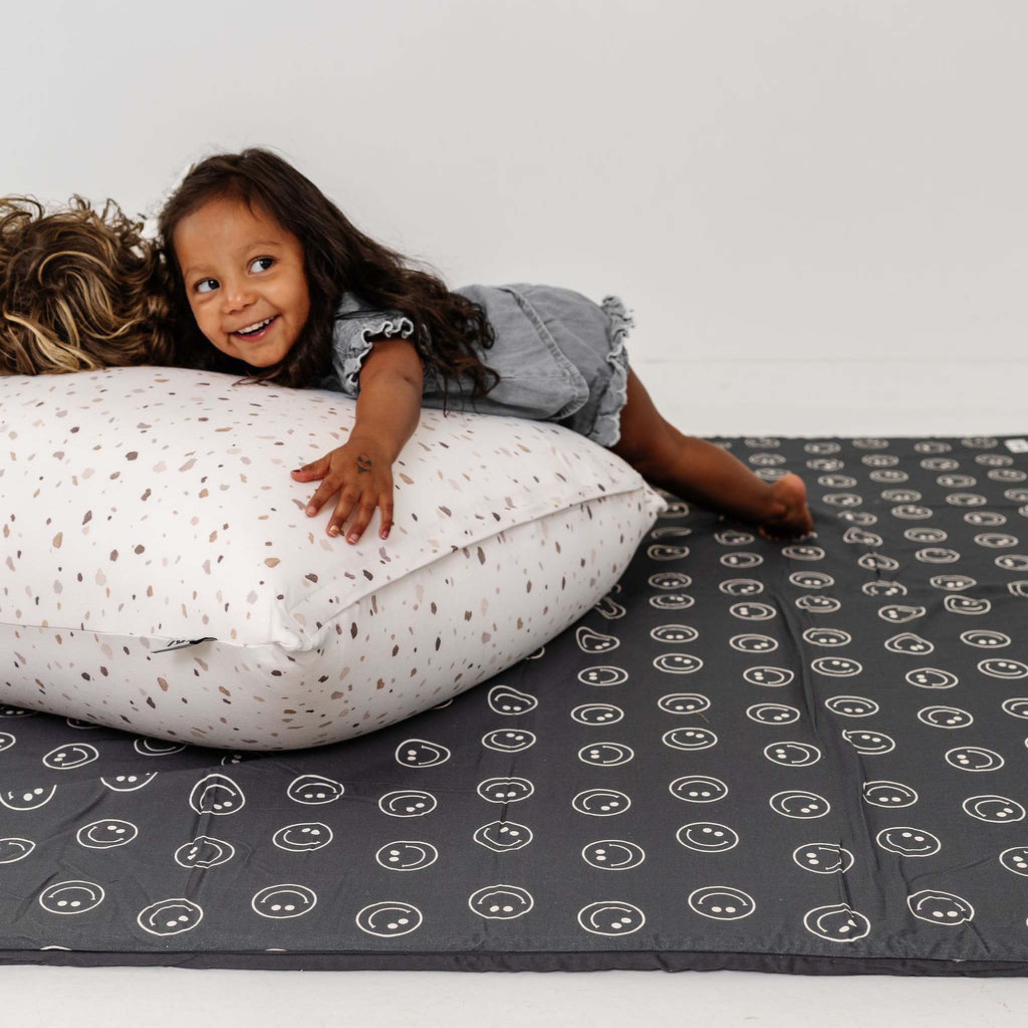 Child playing on a patterned mat with a pillow