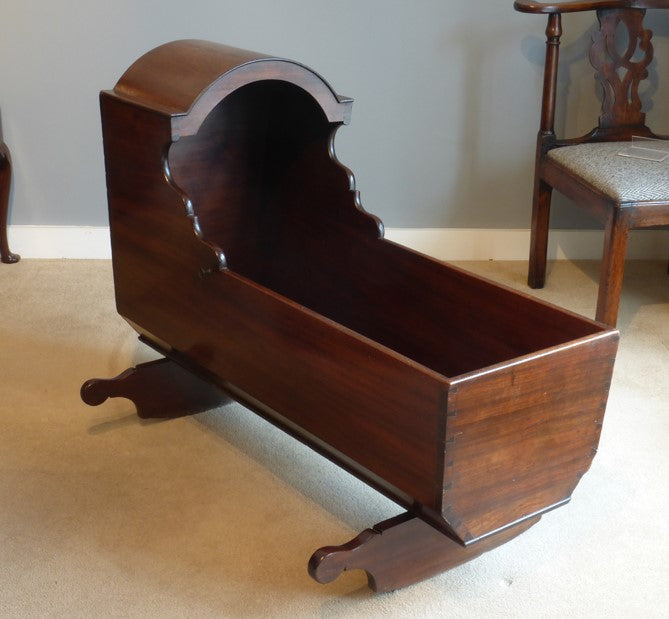 Wooden baby crib in a room with a chair and carpeted floor.
