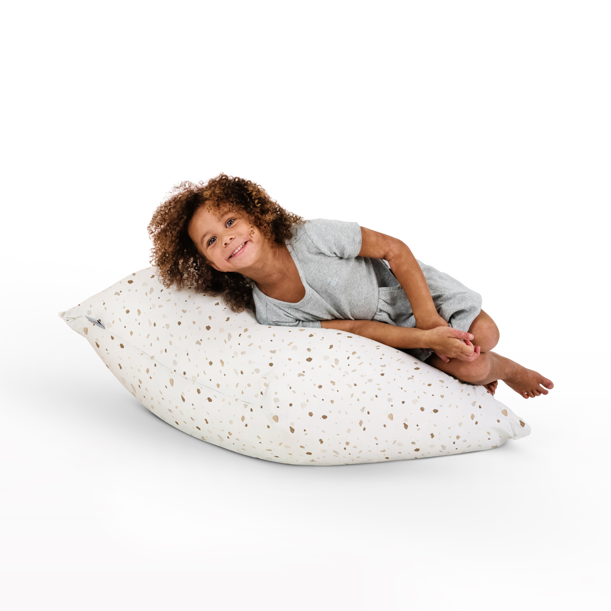 Child sitting on a large pillow with a white background