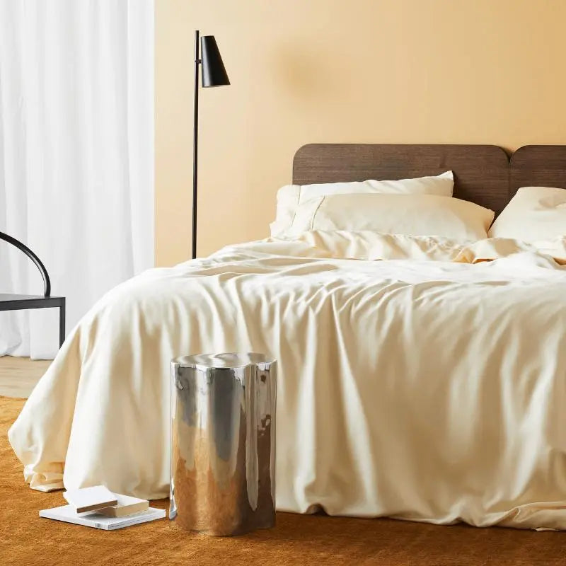 Bedroom with beige bedding, wooden headboard, and a floor lamp.