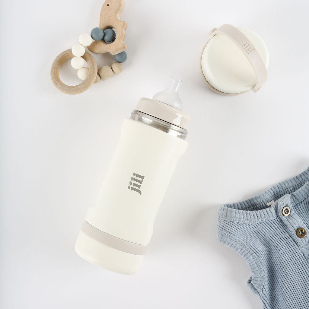 Baby bottle, teething ring, and baby clothes on a white background