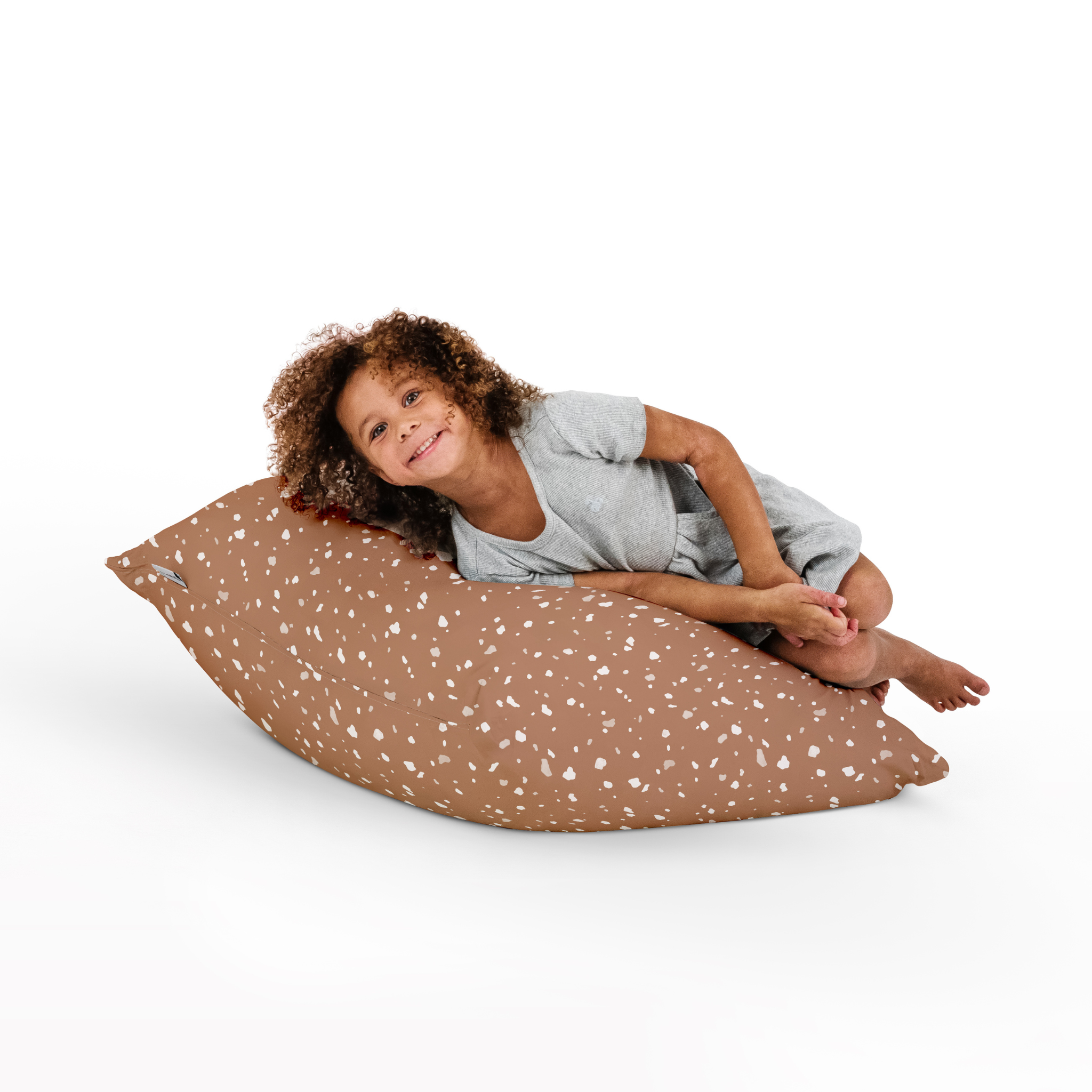 Child sitting on a brown spotted bean bag chair against a white background