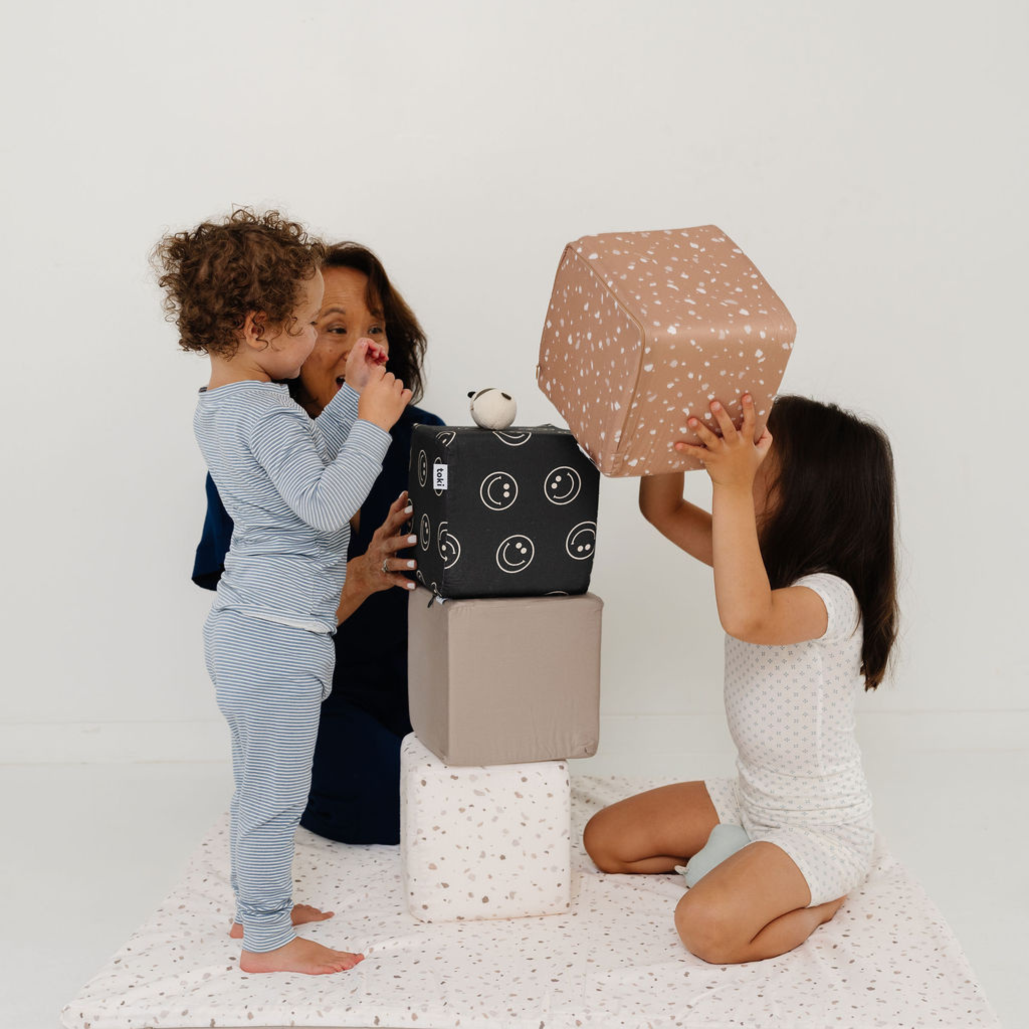 Two children playing with a box and a geometric shape on a white background