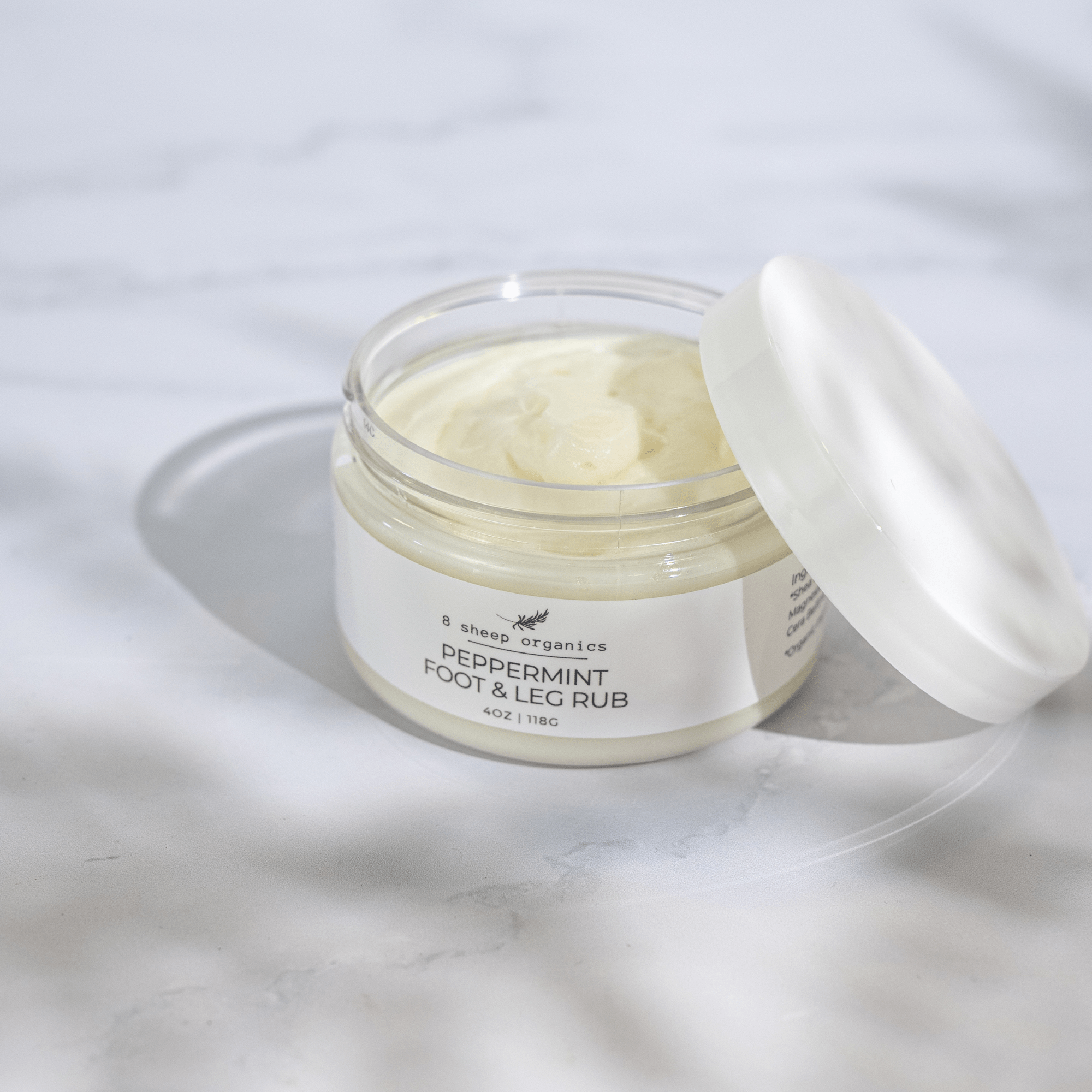 Jar of peppermint foot and leg rub with a white lid on a light gray background