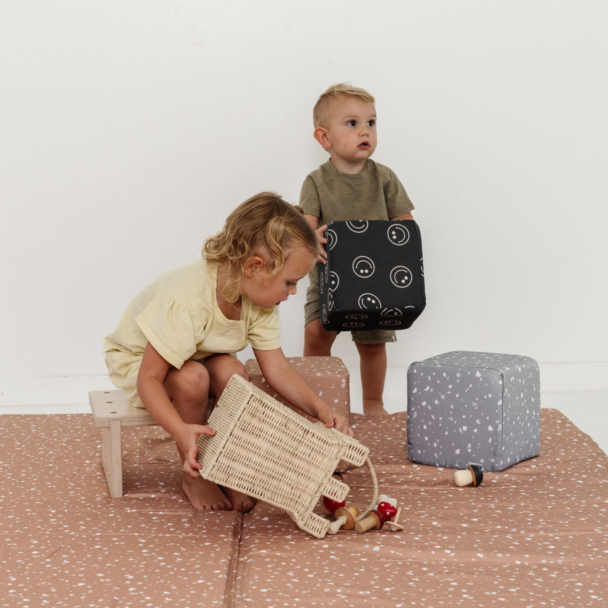 Two children playing with toys on a patterned floor.