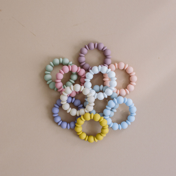 Set of colorful silicone teething rings on a beige background