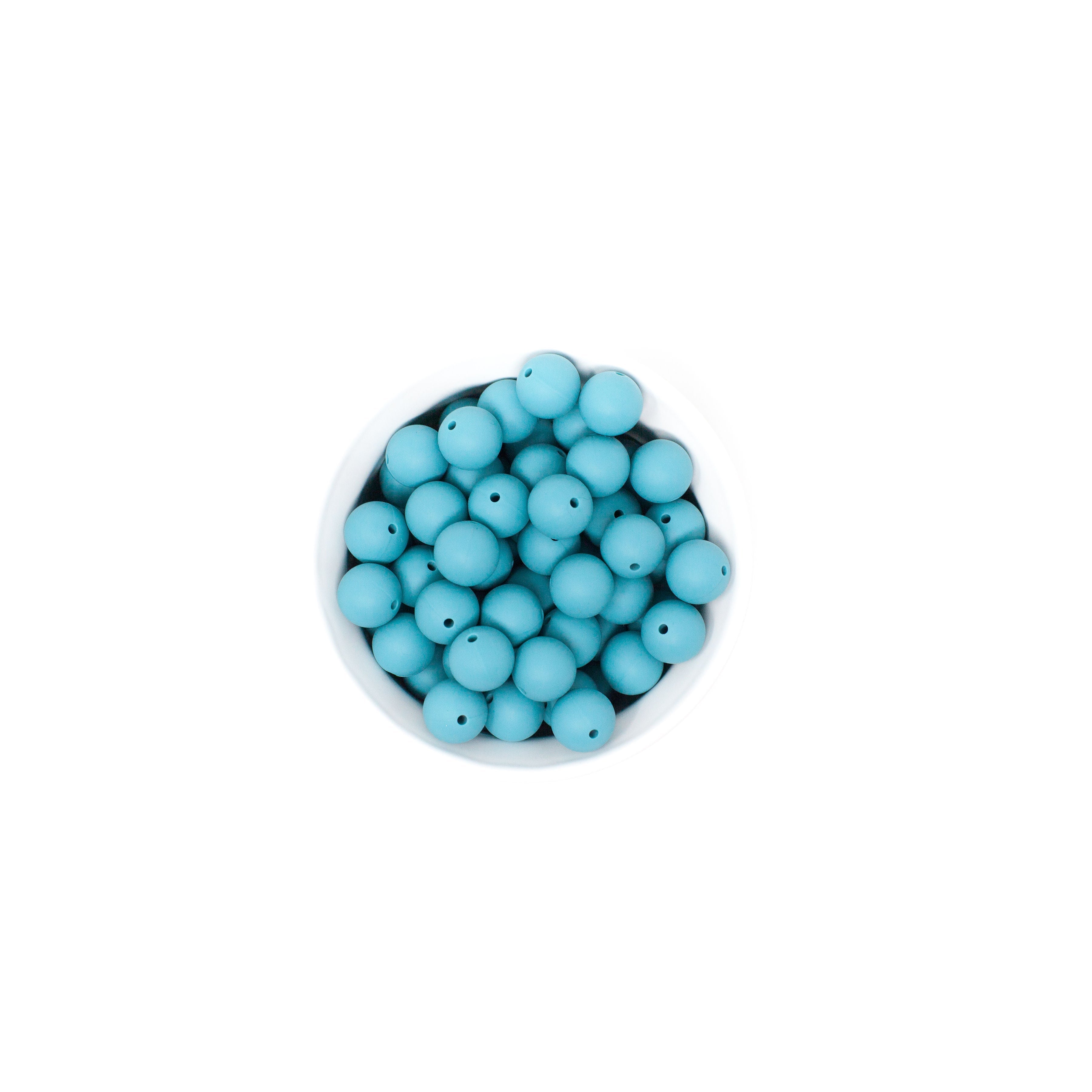 Turquoise beads in a small white bowl on a white background