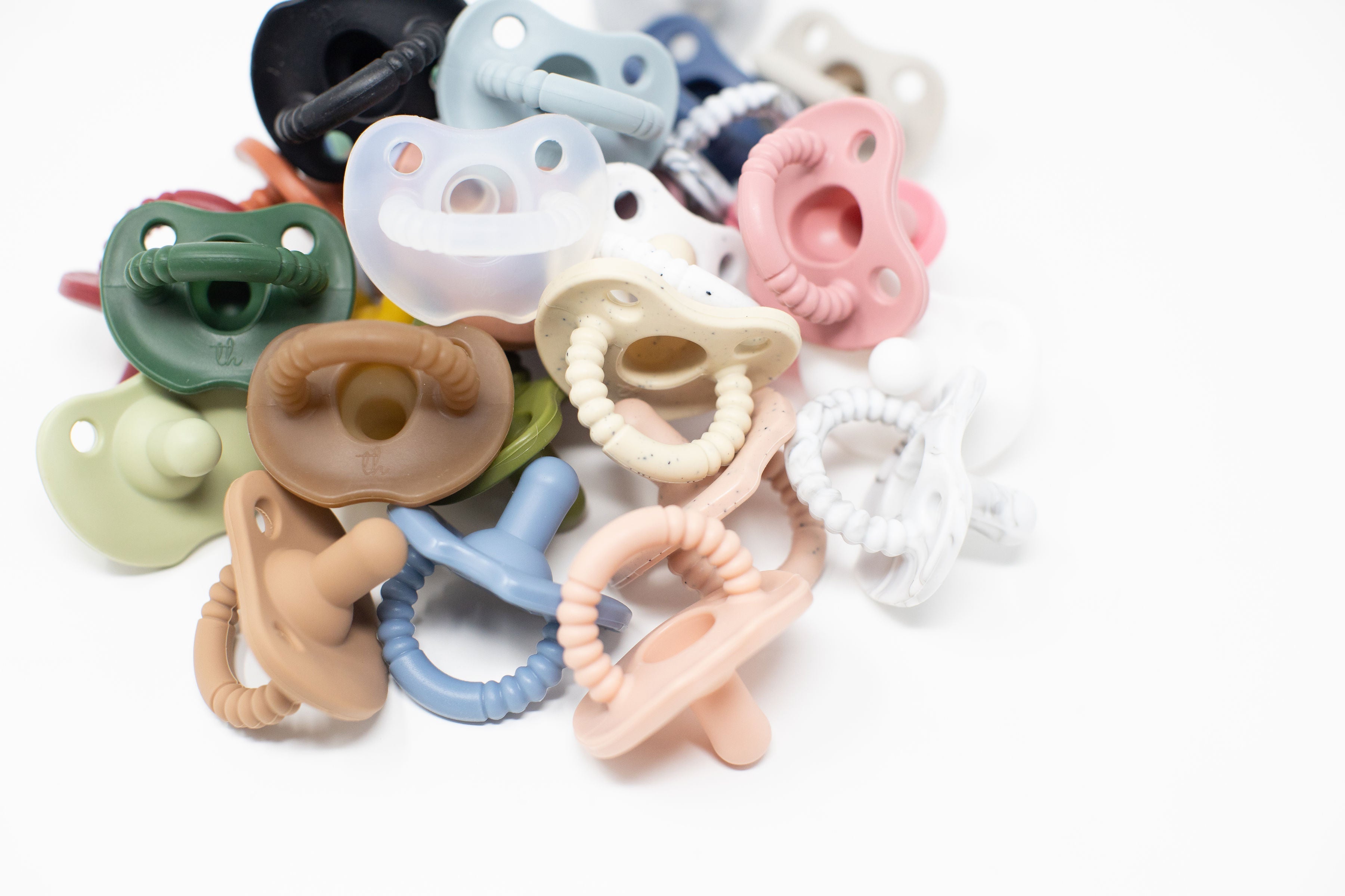 Assorted colorful baby pacifiers and teething rings on a white background