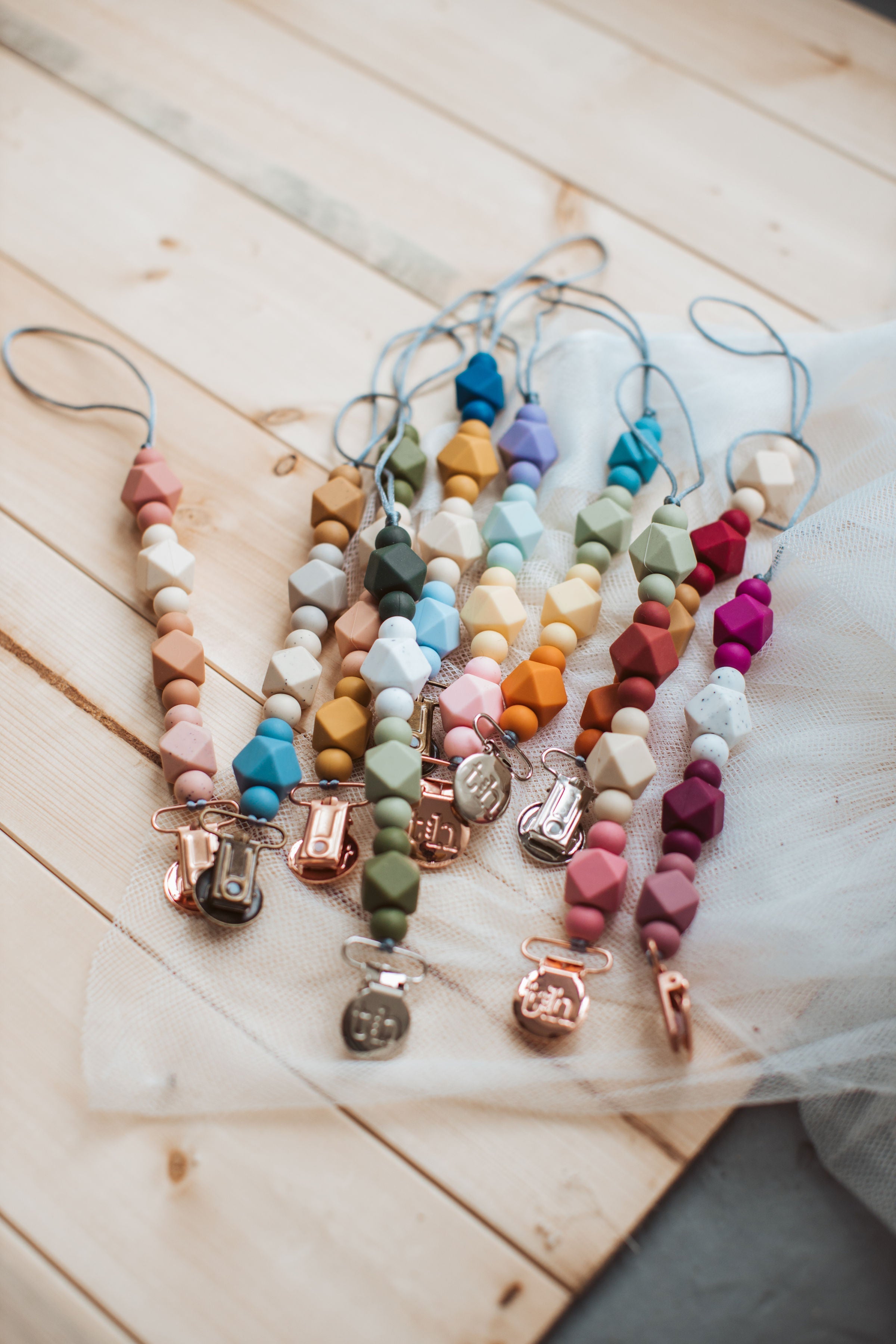 Colorful baby teething necklaces on a wooden surface