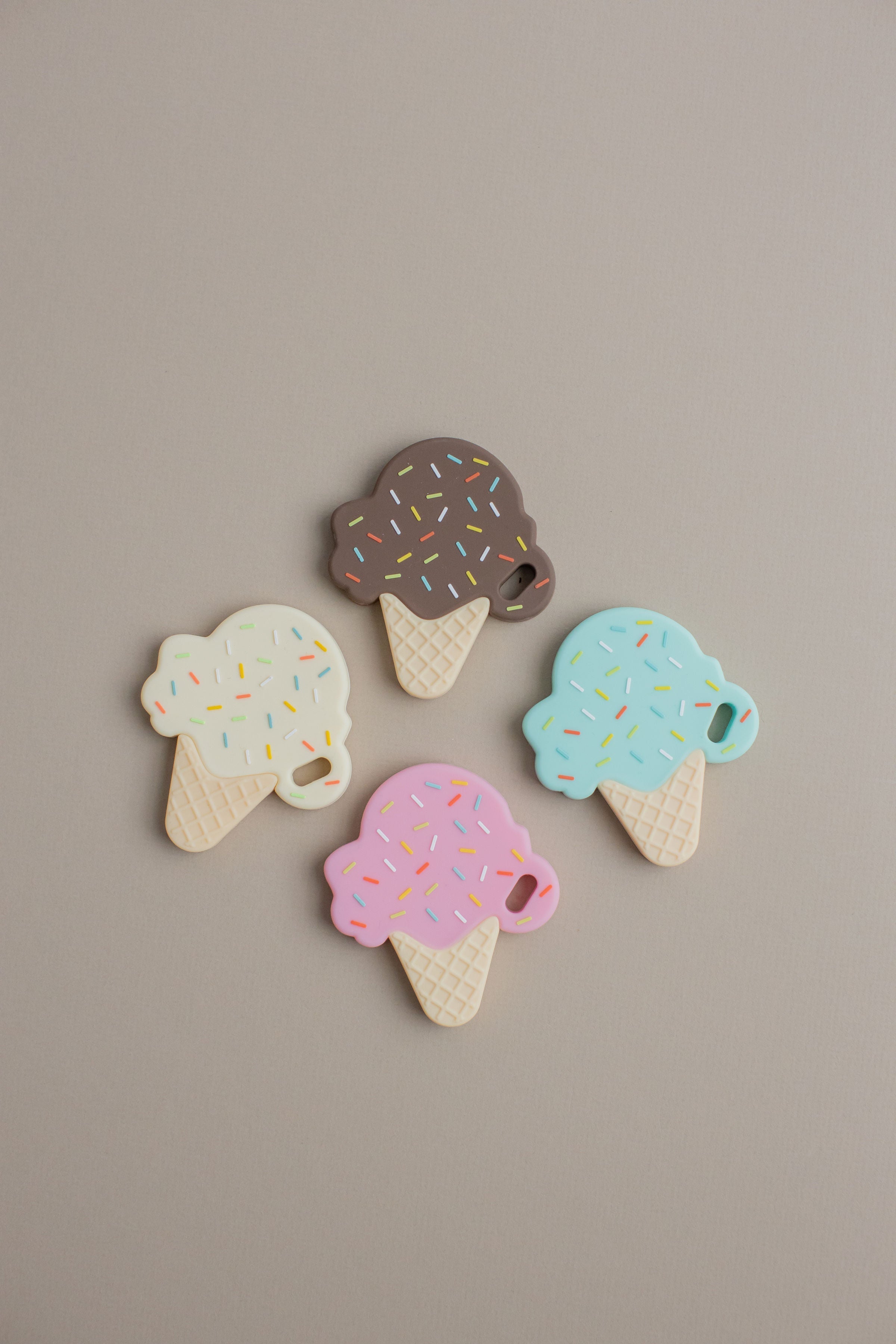 Four colorful ice cream cone-shaped cookies on a beige background