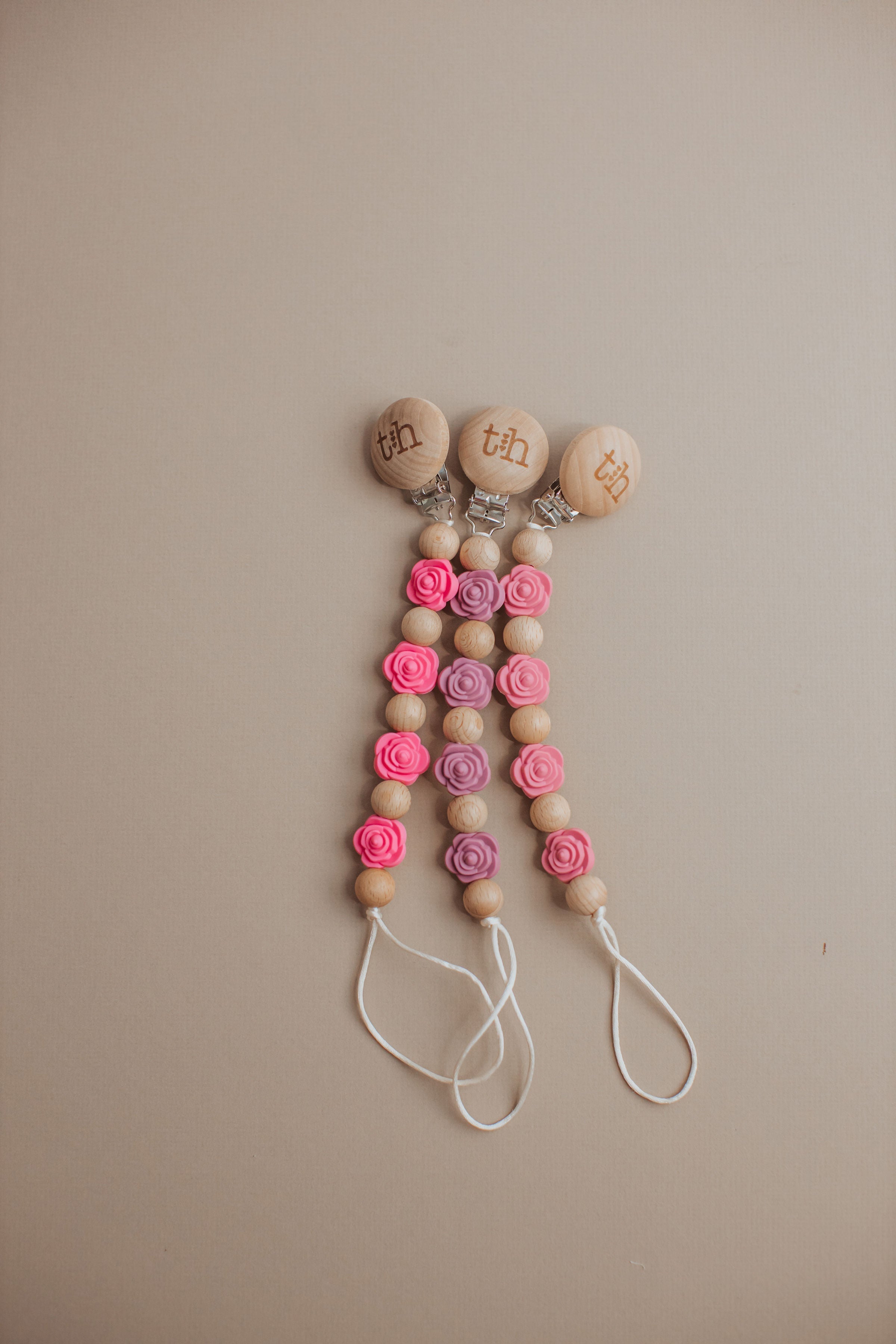 Decorative keychain with wooden beads and pink flowers on a beige background