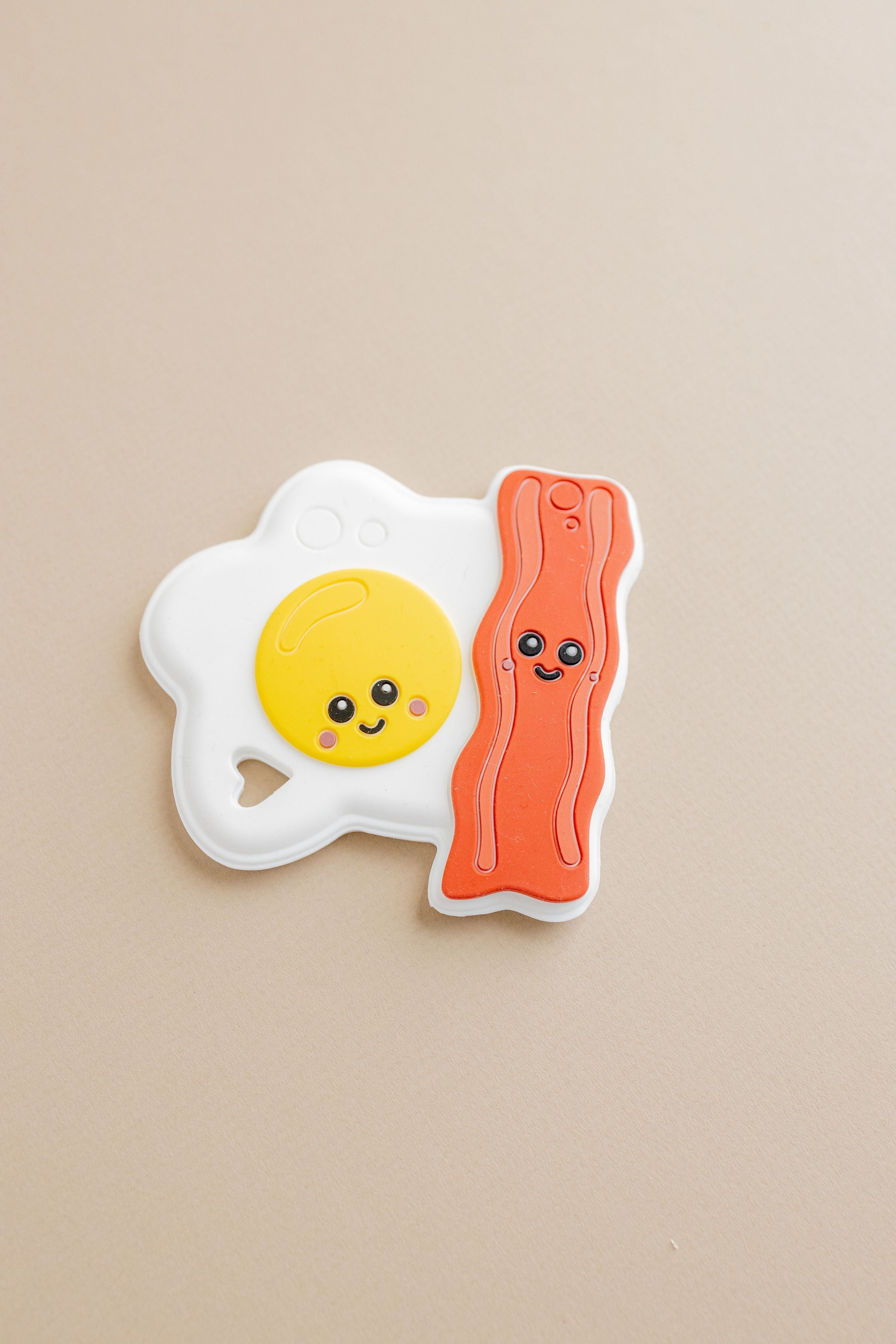 Fridge magnet shaped like a smiling fried egg and bacon on a beige background