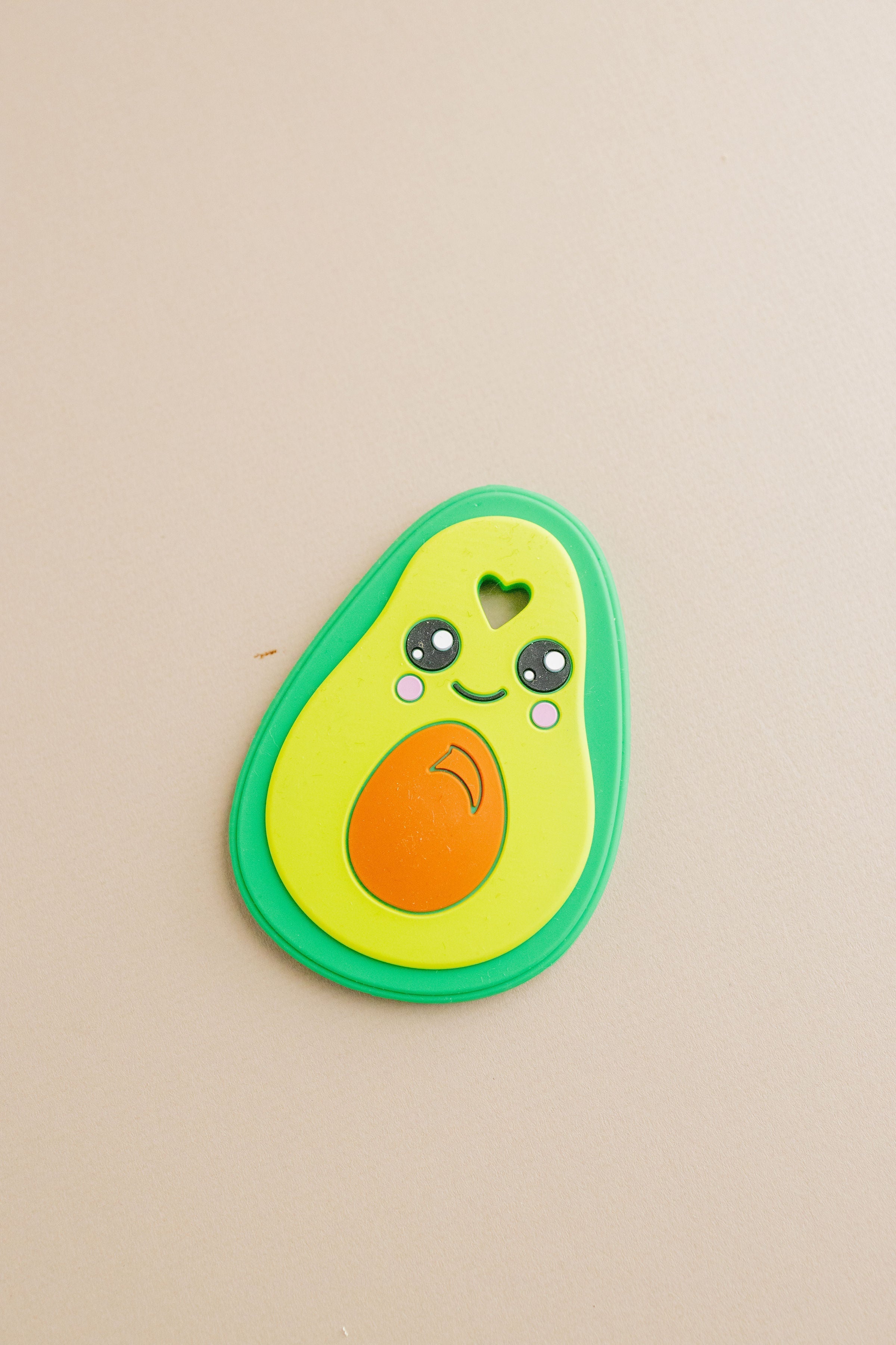 Avocado-shaped toy with a smiling face on a beige background