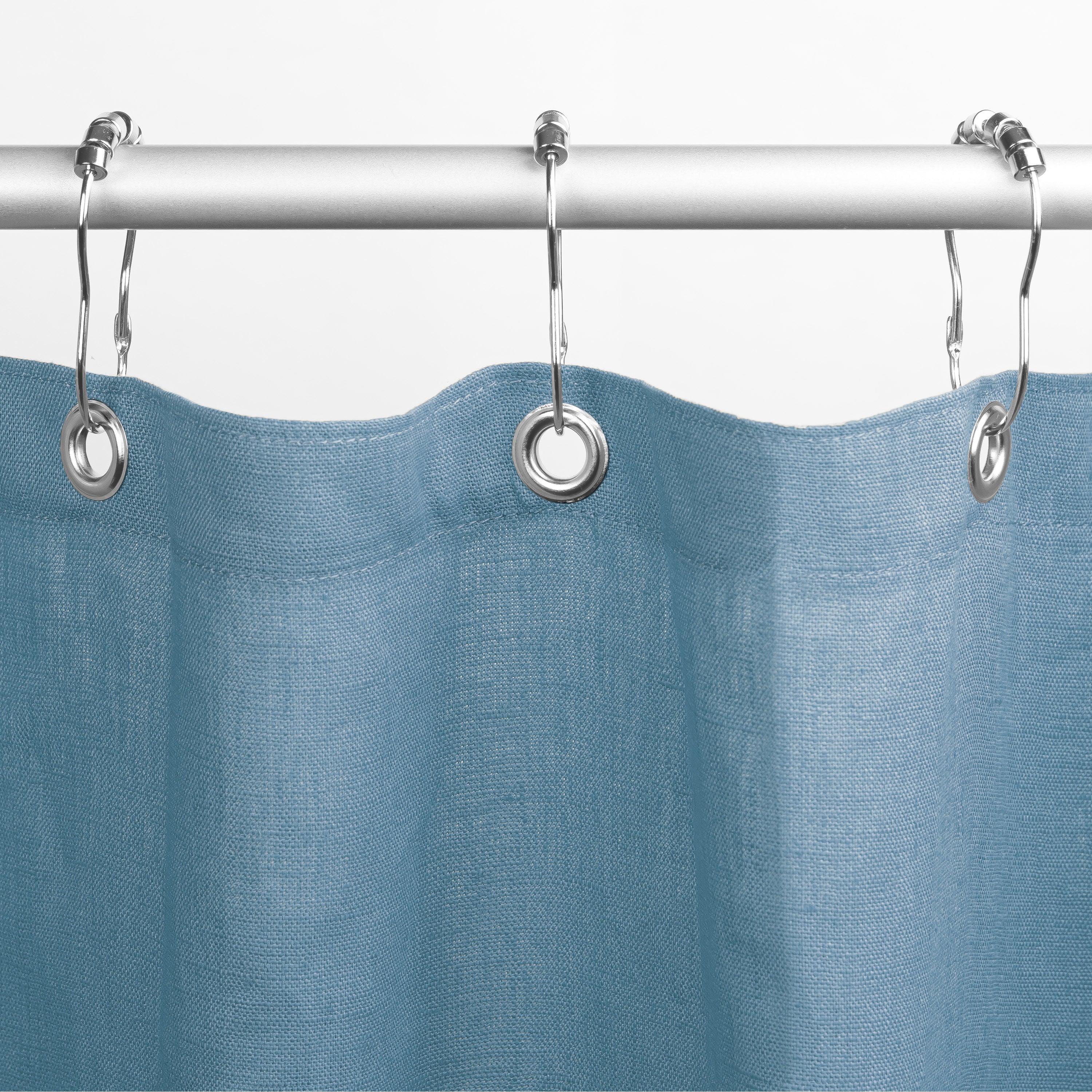 Blue shower curtain with silver hooks on a white background